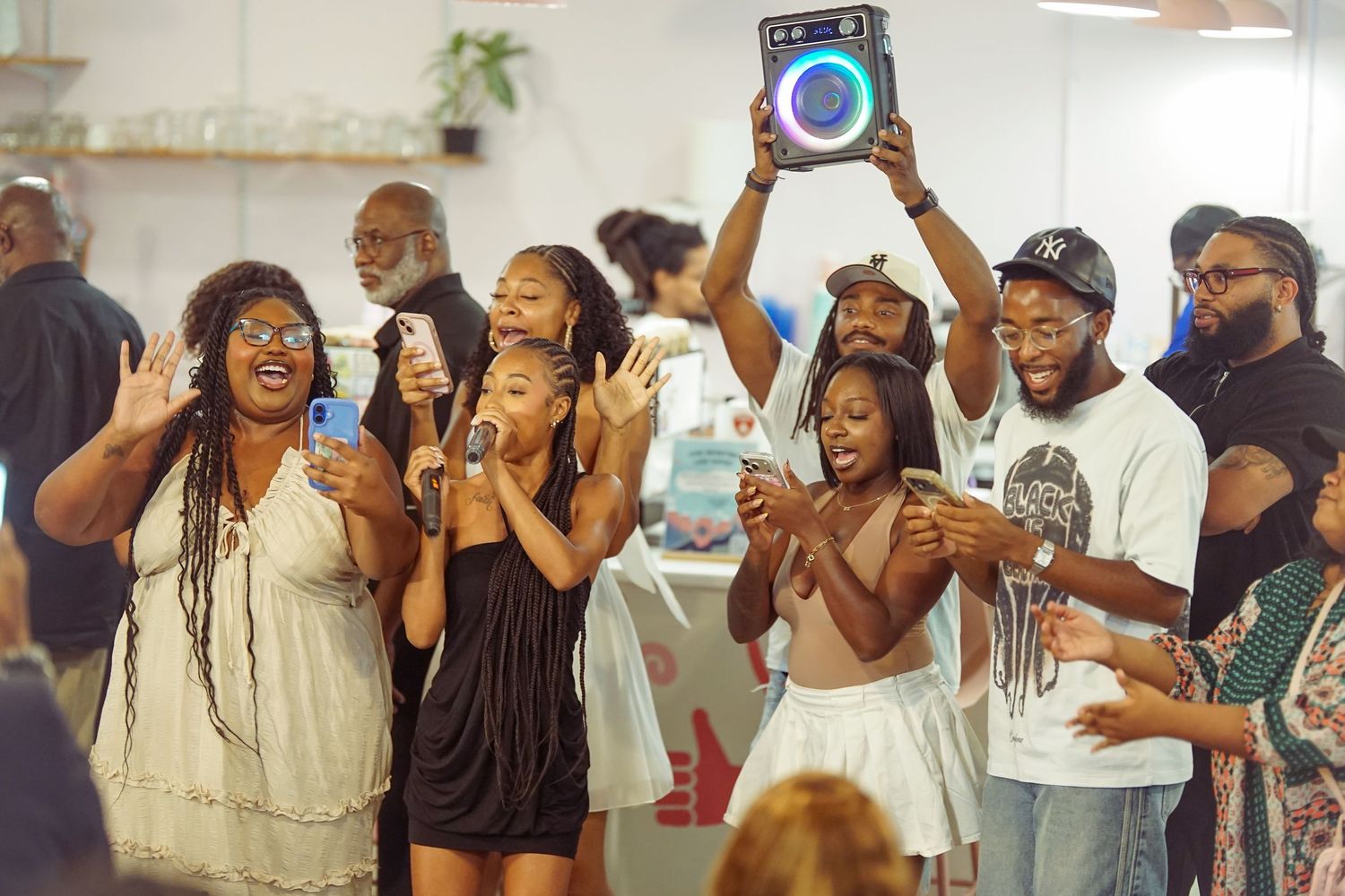 A joyful group of people dancing and celebrating indoors, with one person raising a boombox overhead at a lively party.