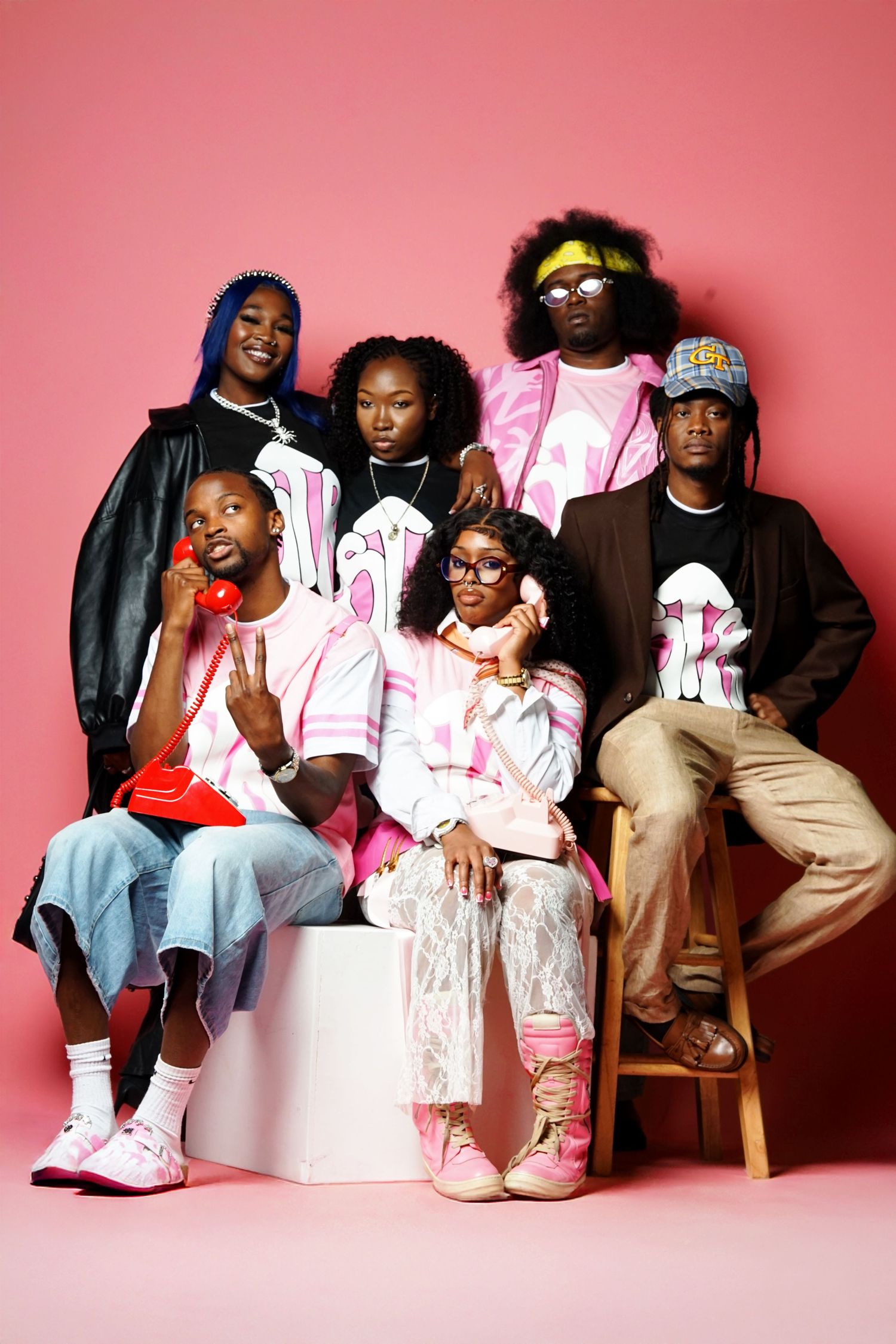 Fashion models pose together on white blocks wearing coordinated urban streetwear.