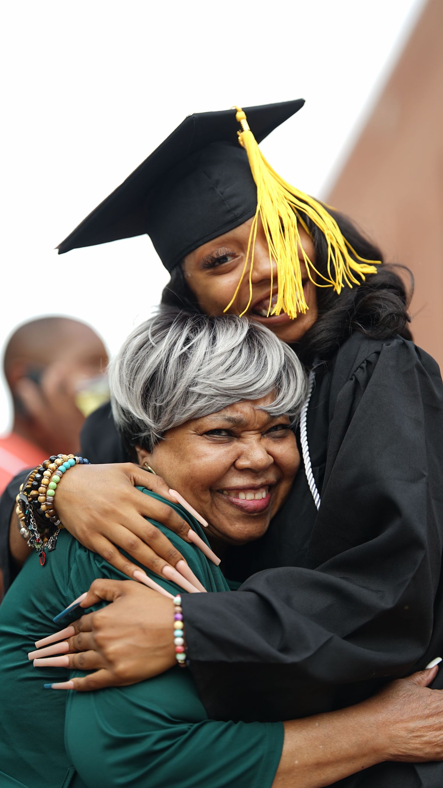 Heartwarming hug between graduate and supporter during graduation celebration.
