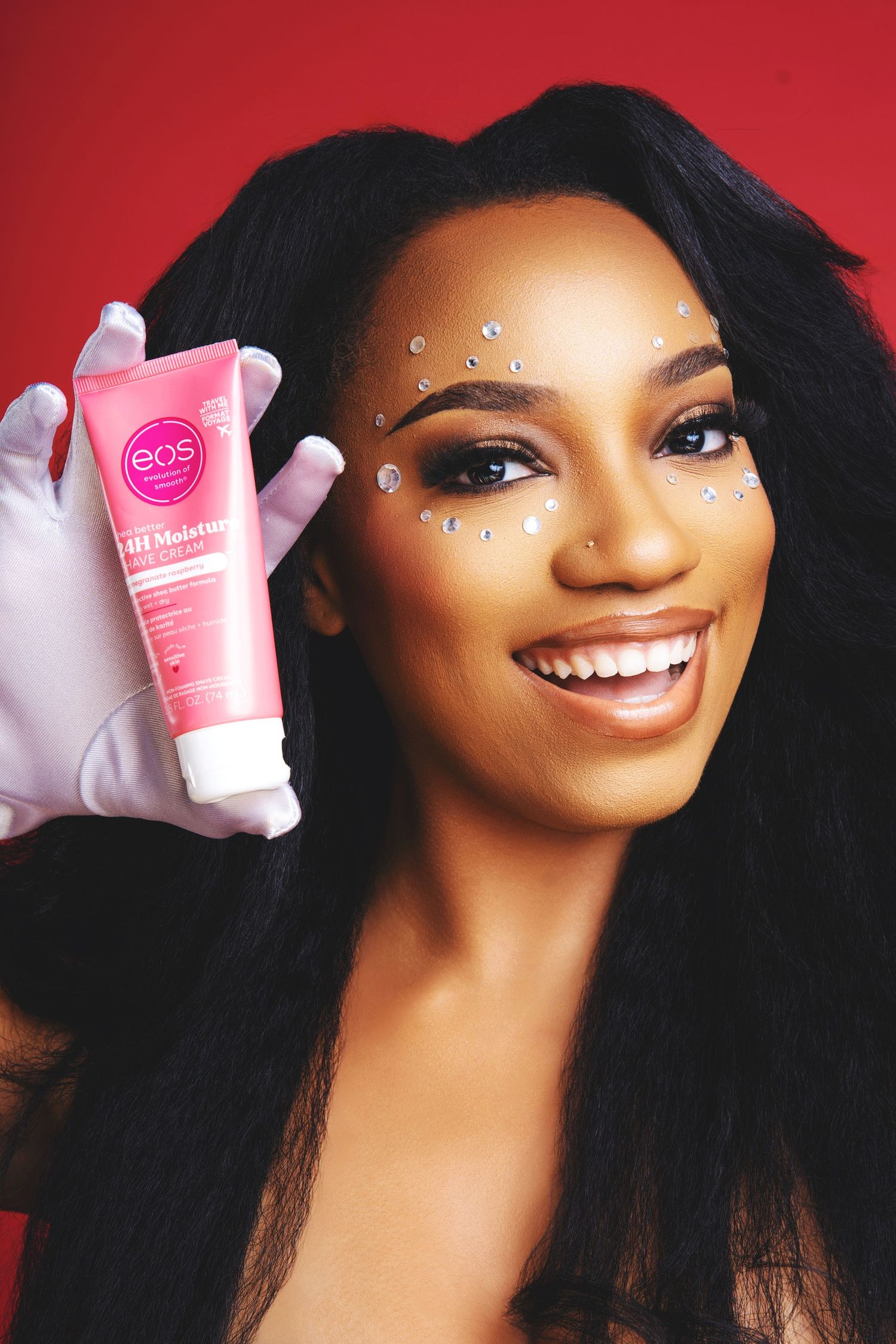Beauty product photography featuring pink cosmetics bottles and white gloves against red background.