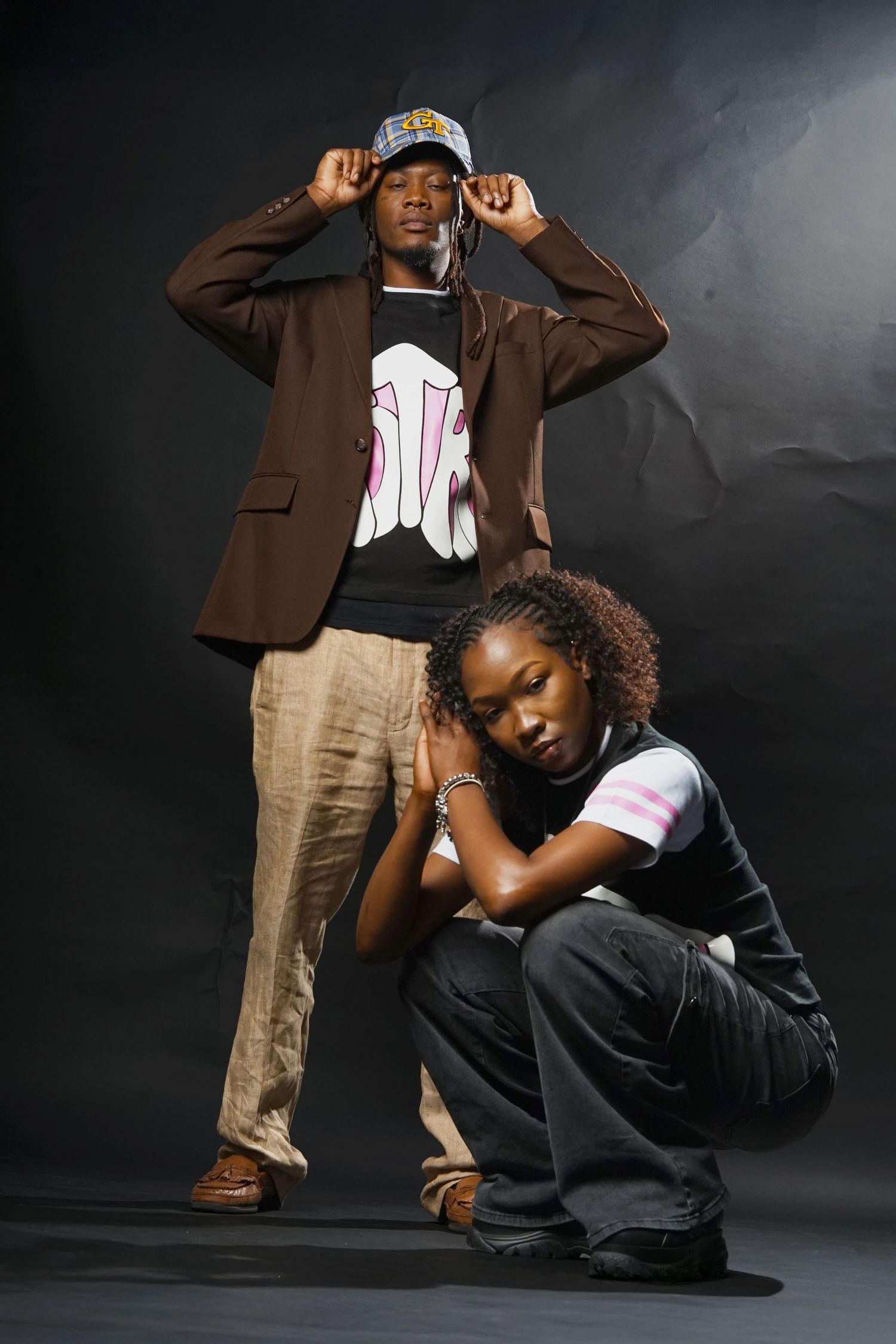 Two models in contrasting poses wearing matching graphic tees and urban streetwear.