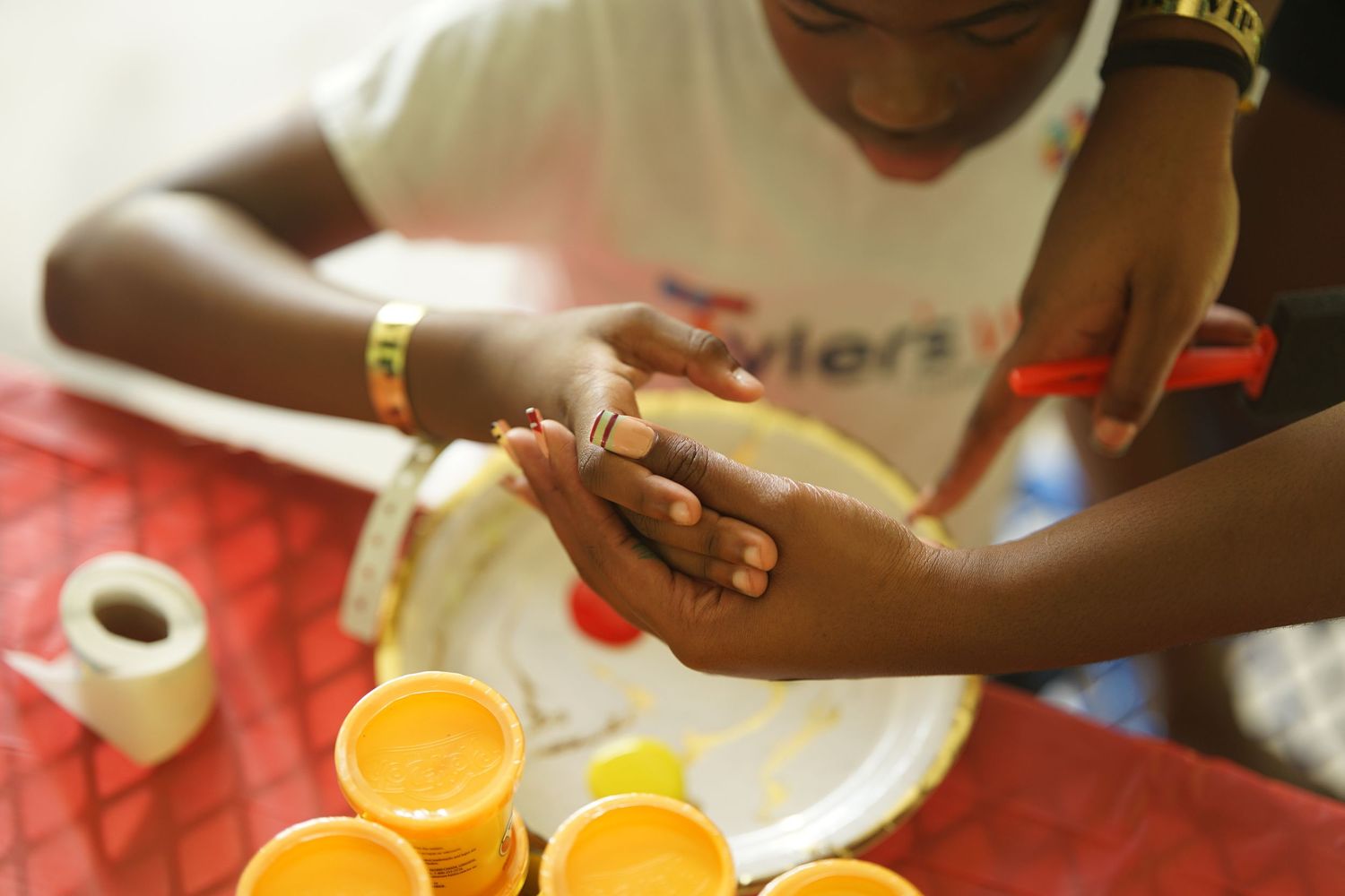 Close-up of hands holding colorful paint on a white palette during an art activity.