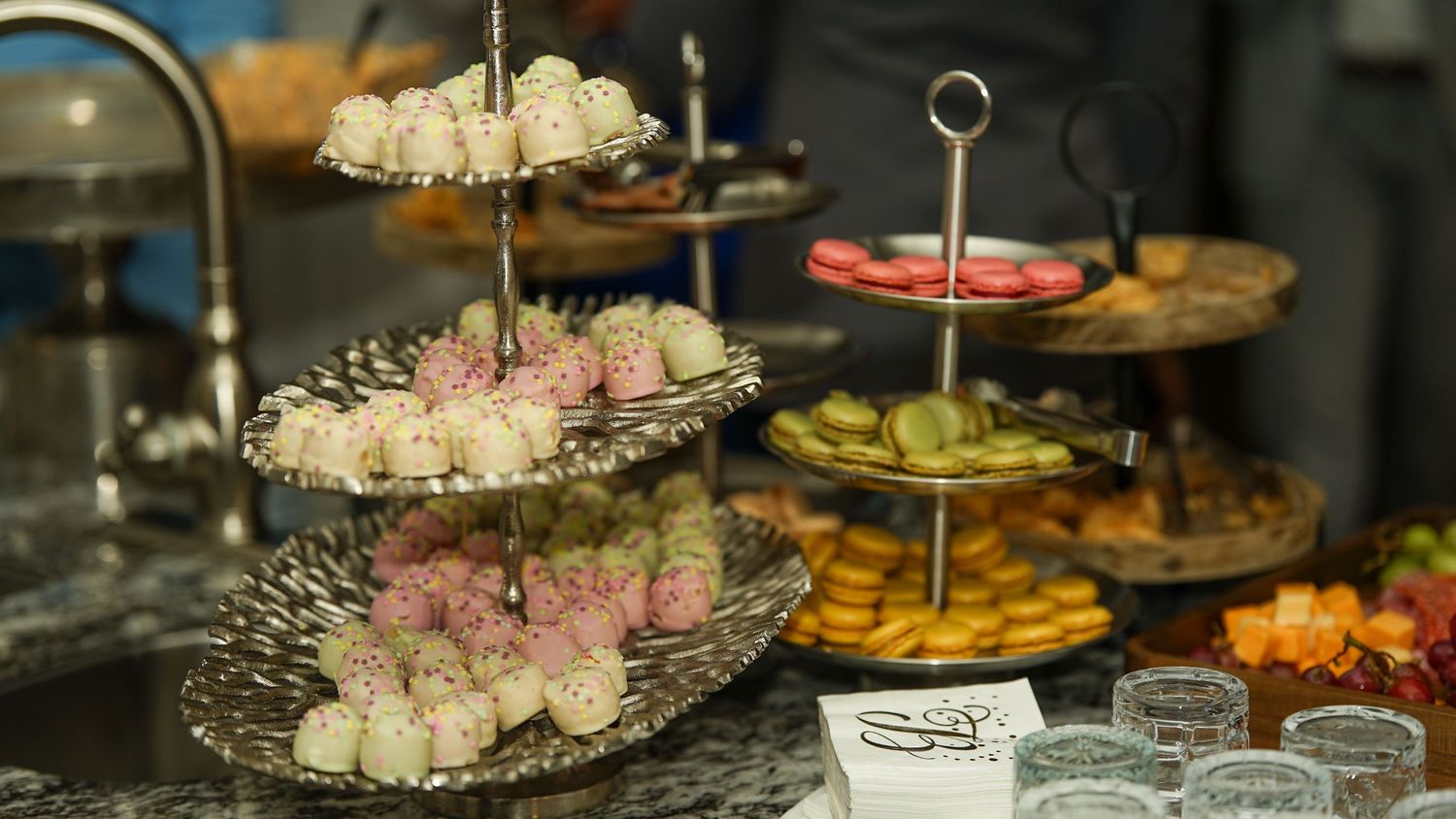Elegant tiered dessert display with assorted pastries and treats on silver platters.