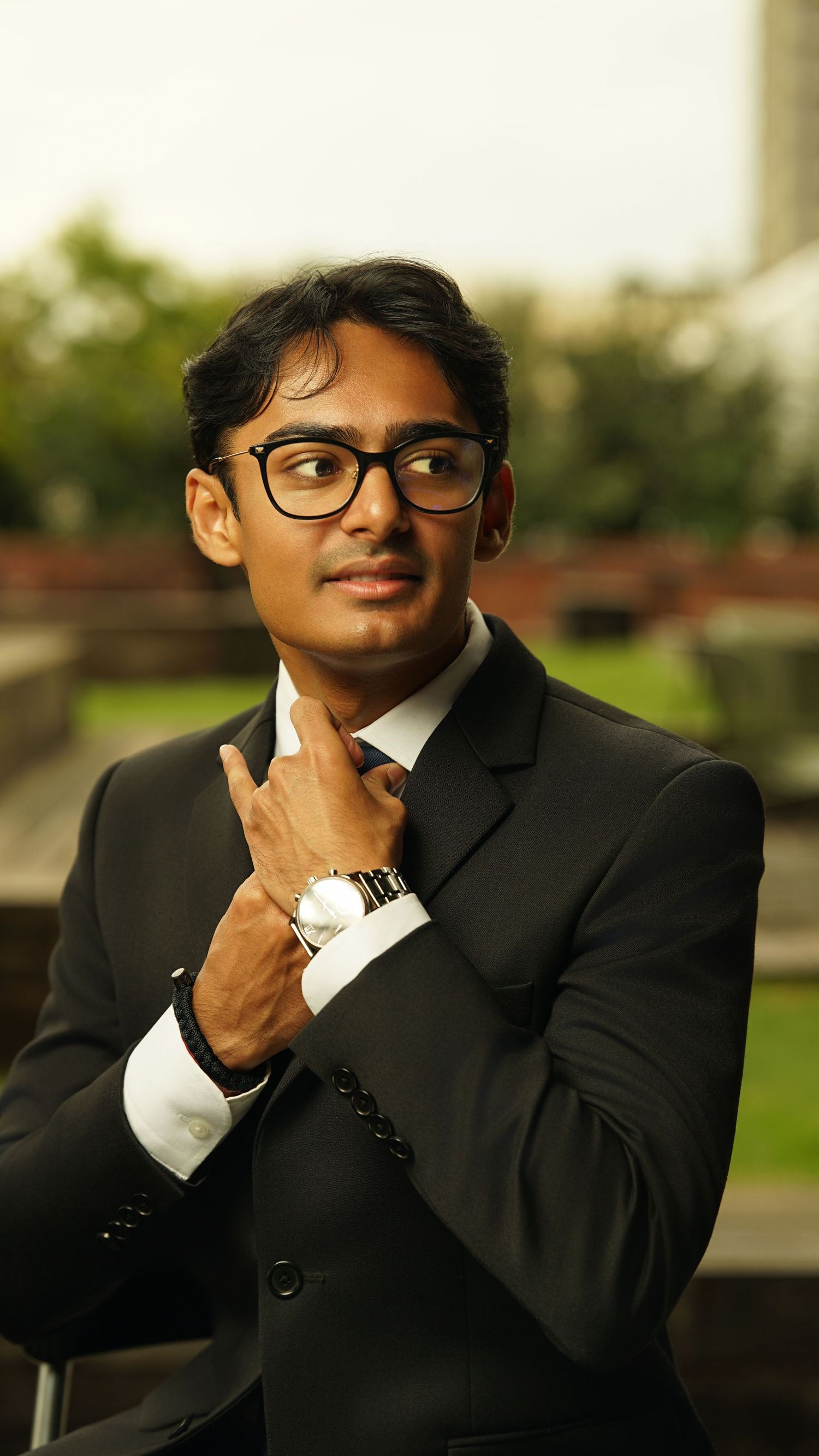 Thoughtful pose of person in formal business attire with glasses resting hand on chin.