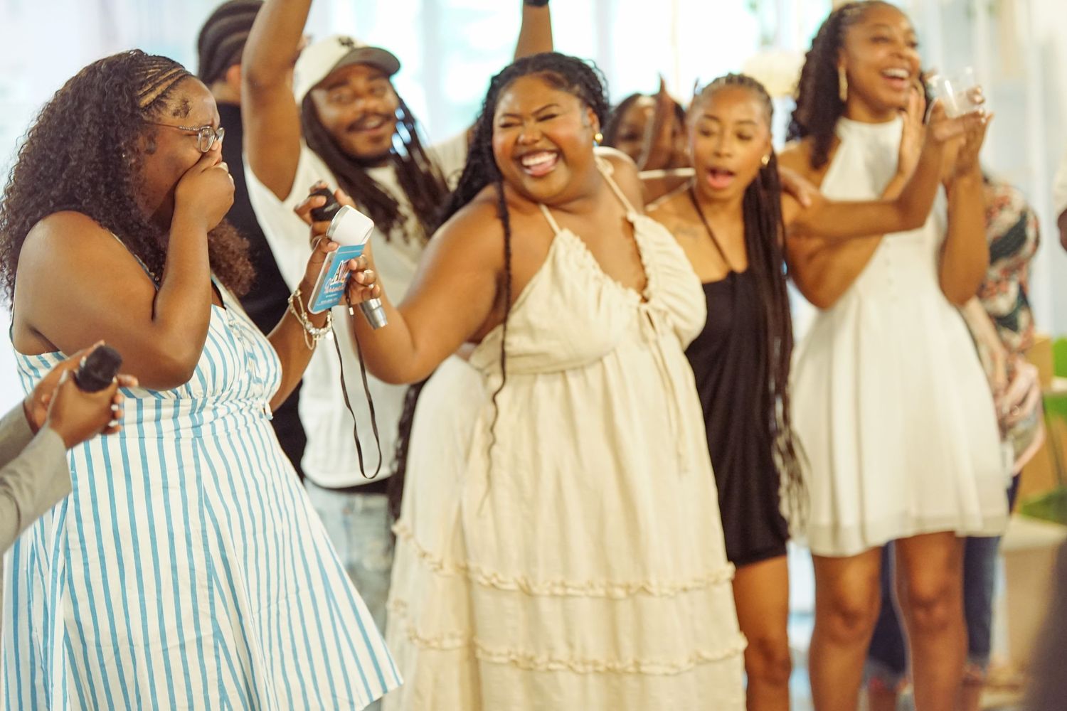 Group of joyful people dancing and celebrating at a party, wearing white and colorful outfits.