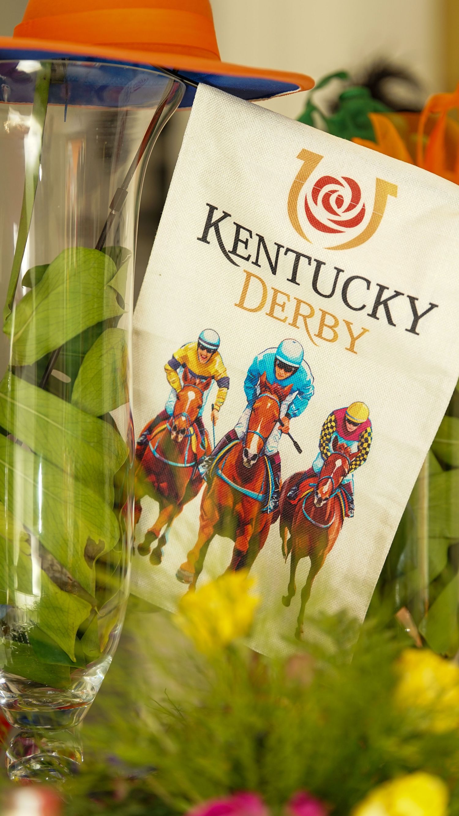 Kentucky Derby program and logo displayed with orange hat and floral decorations.