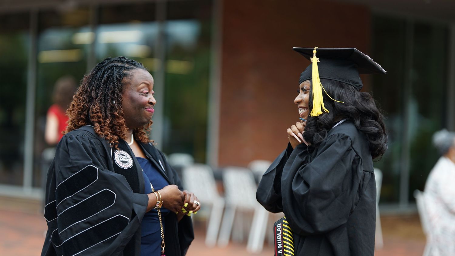 Graduate in cap and gown shares emotional embrace during commencement ceremony.