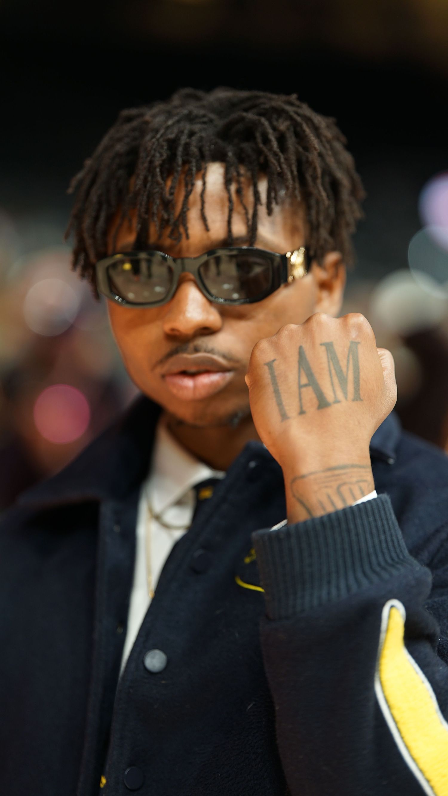 A sequence showing someone in sunglasses and a navy jacket with hand tattoos visible.