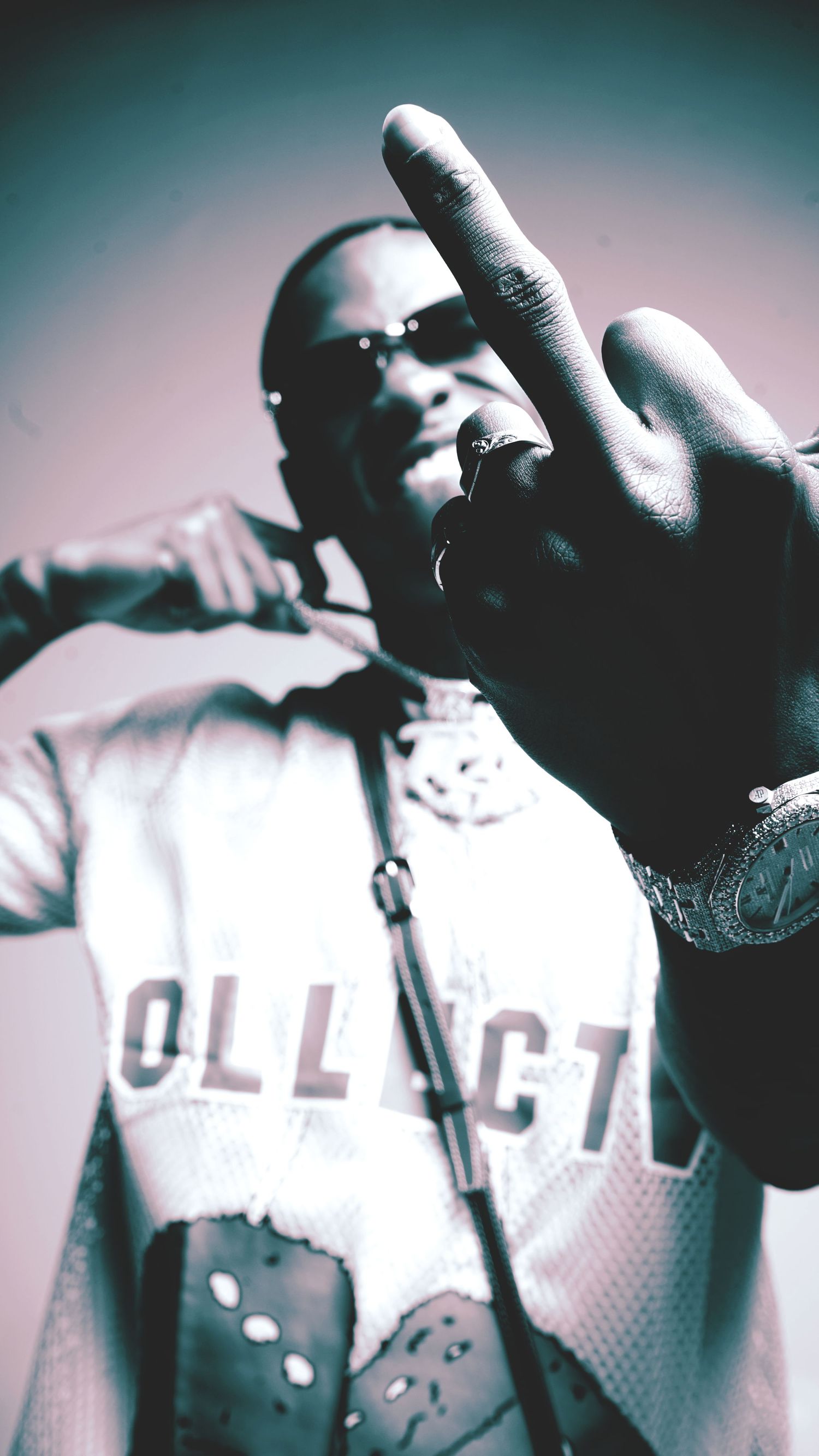 Artist performing on stage wearing college shirt making peace sign gesture.