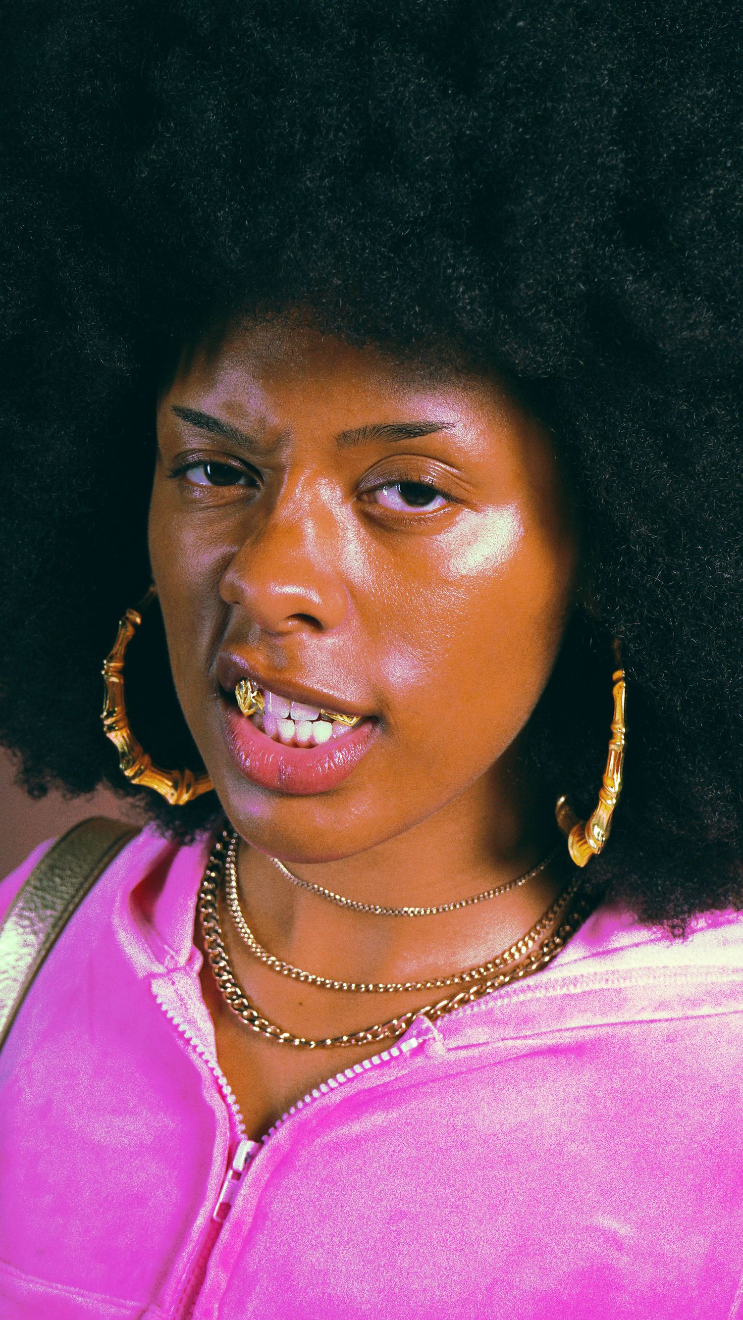 Close-up portrait showcasing gold jewelry and pink fashion details.