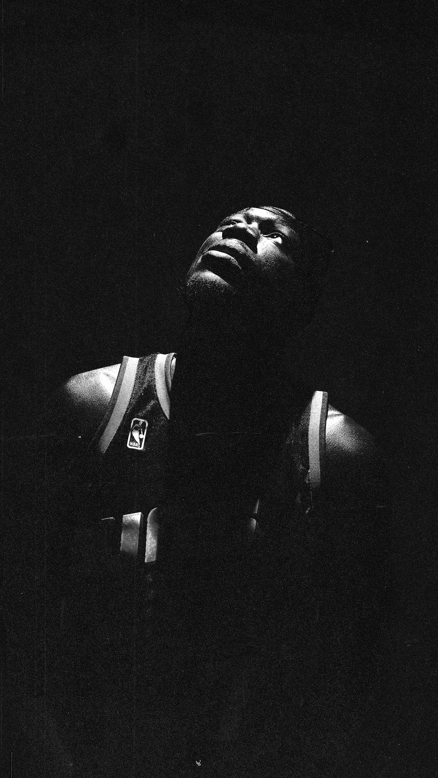 Dramatic low-key photograph showing NBA jersey details in dark lighting.
