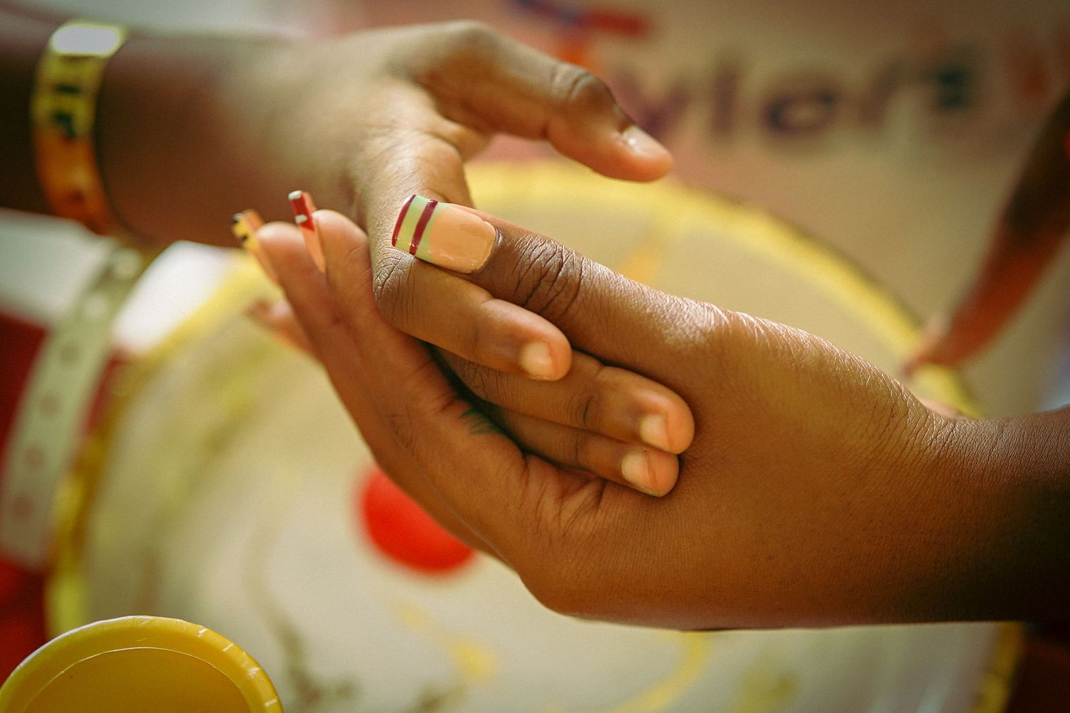 Two dark-skinned hands exchanging a ring during a traditional wedding ceremony, symbolizing love and commitment.