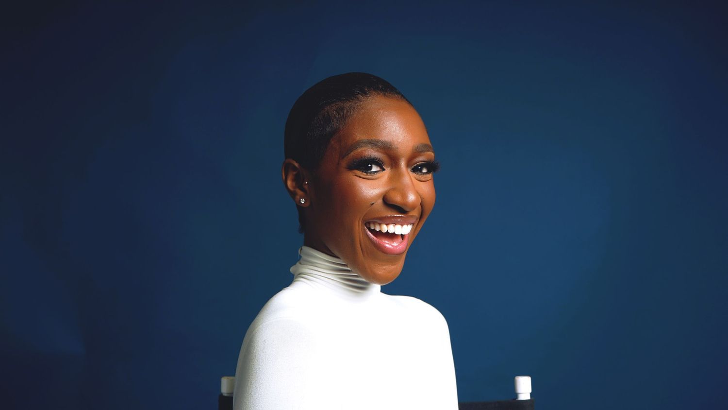 Professional studio portrait against deep blue background showing joyful expression.
