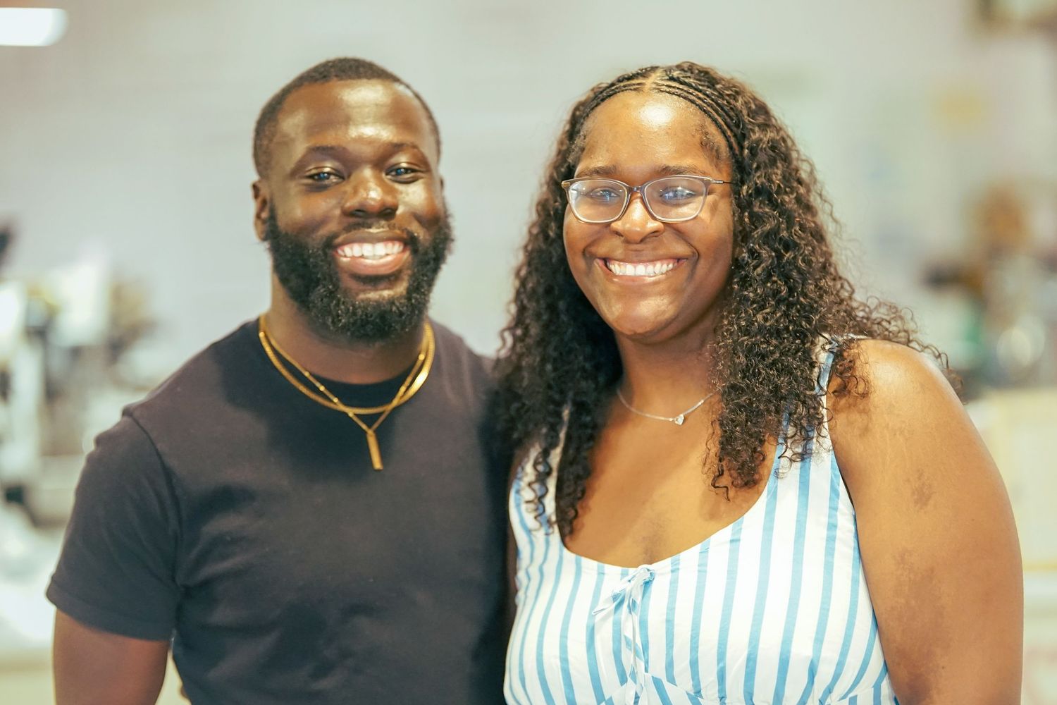 A smiling Black couple posing together indoors at a social event.