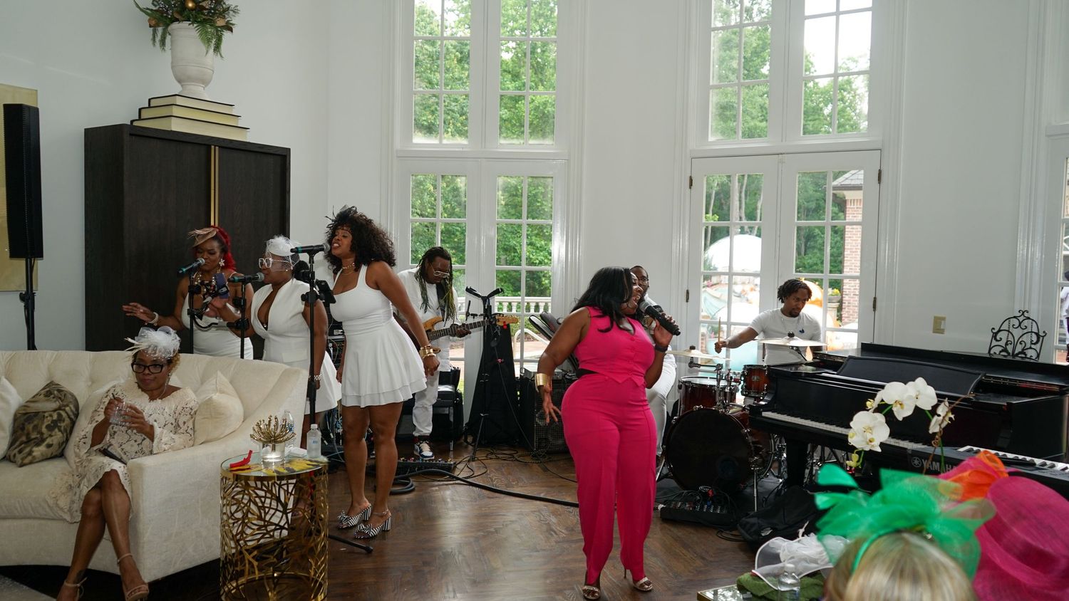 A panoramic view of an elegant white indoor venue with large windows and party decorations.