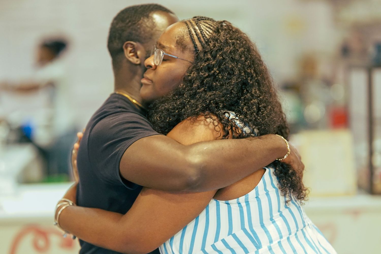 Two people sharing a warm embrace hug at a casual indoor social gathering event.