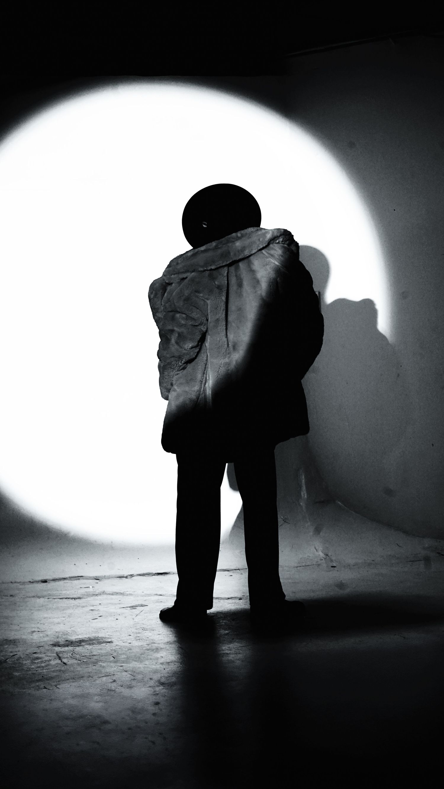 Dramatic black and white silhouettes of feet walking through a dimly lit space with strong shadows.
