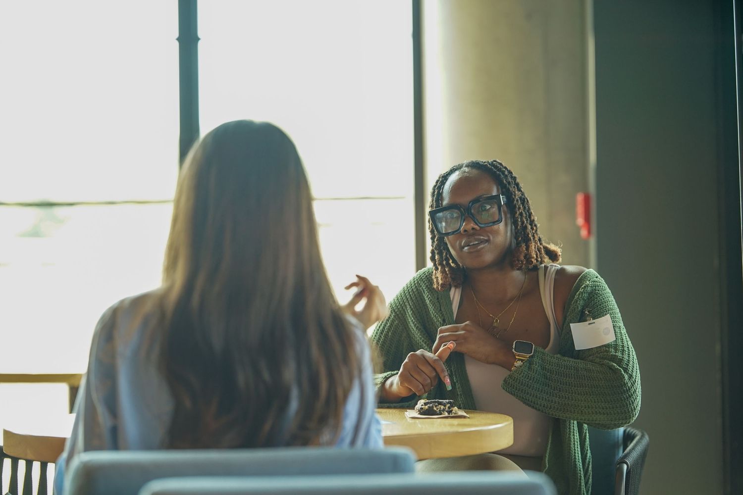 Two women engaged in conversation at a table during a professional networking event.