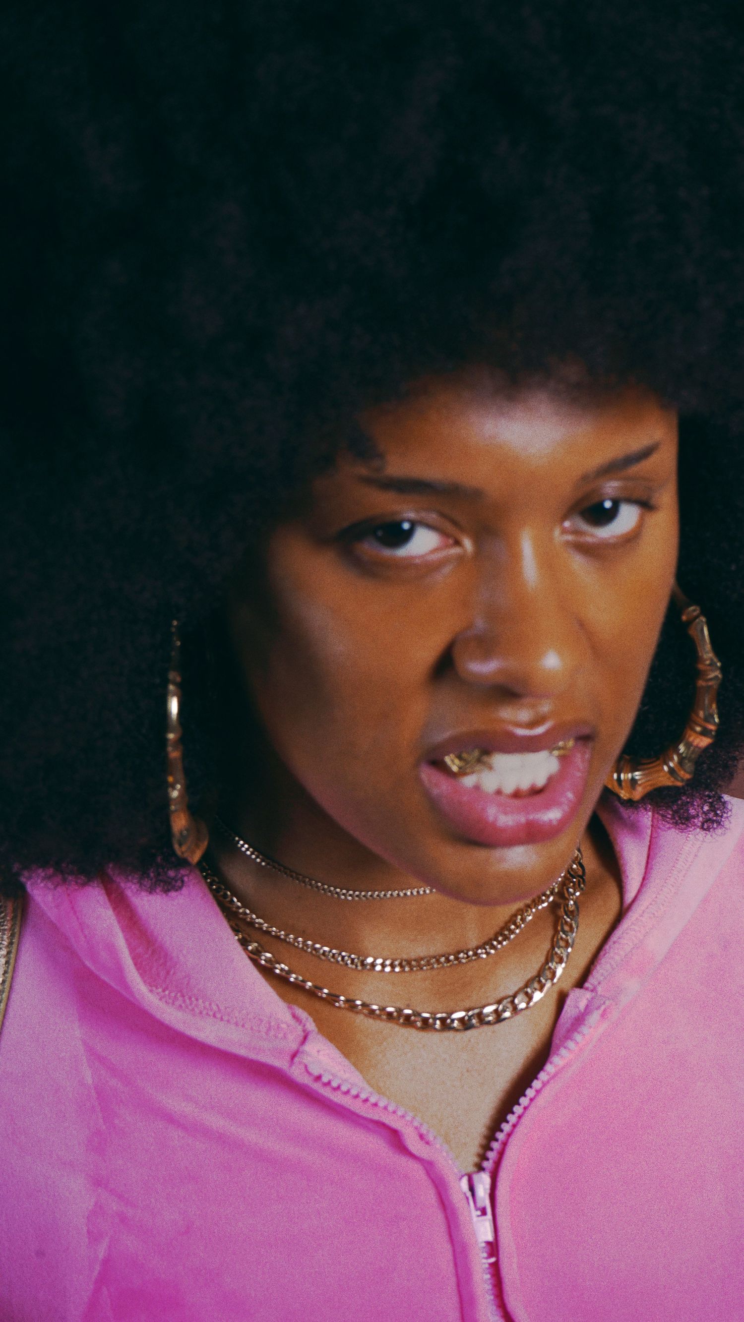 Close-up portrait showing pink outfit and gold chain necklace details.