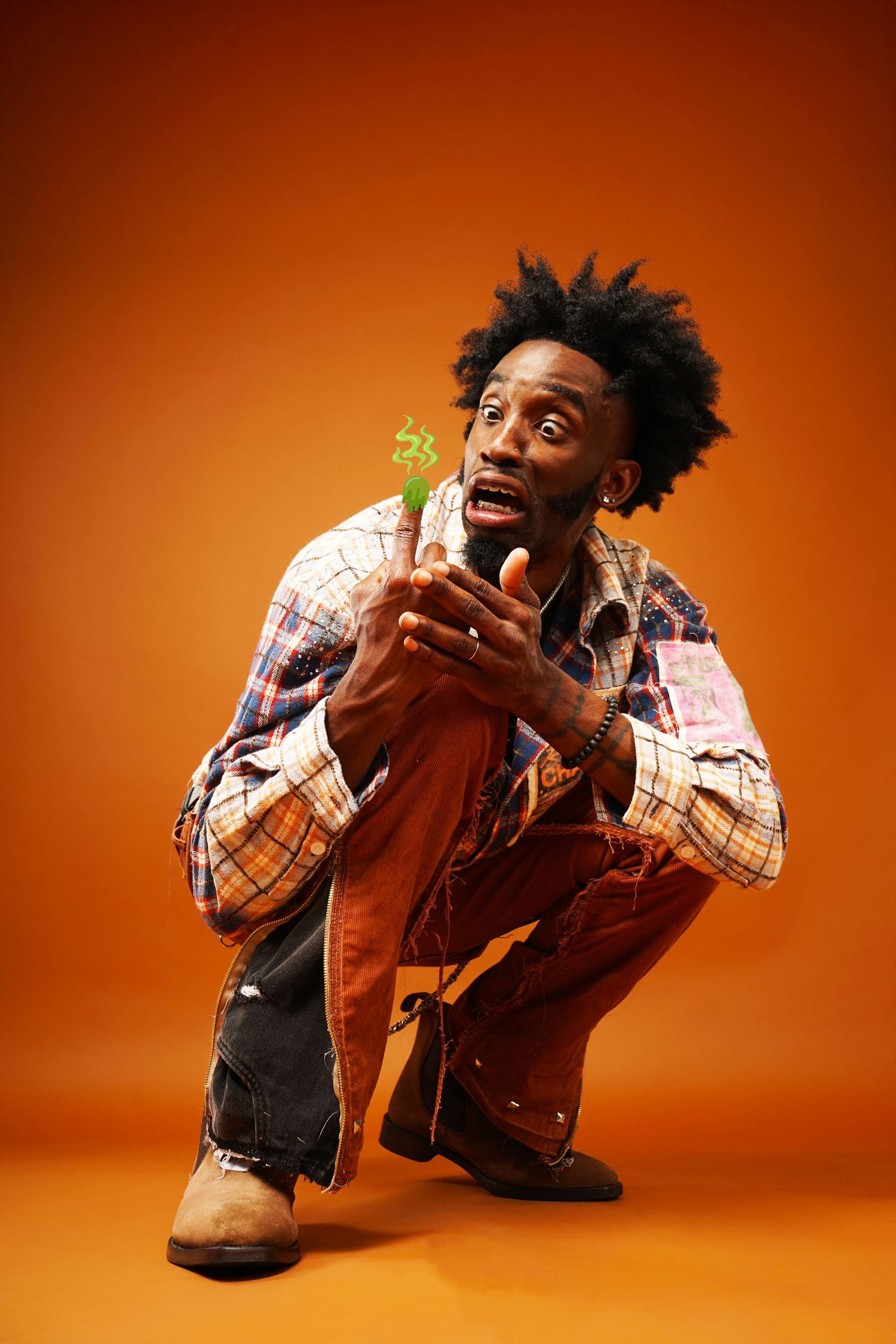 Crouching pose examining small object with interest against orange studio backdrop.