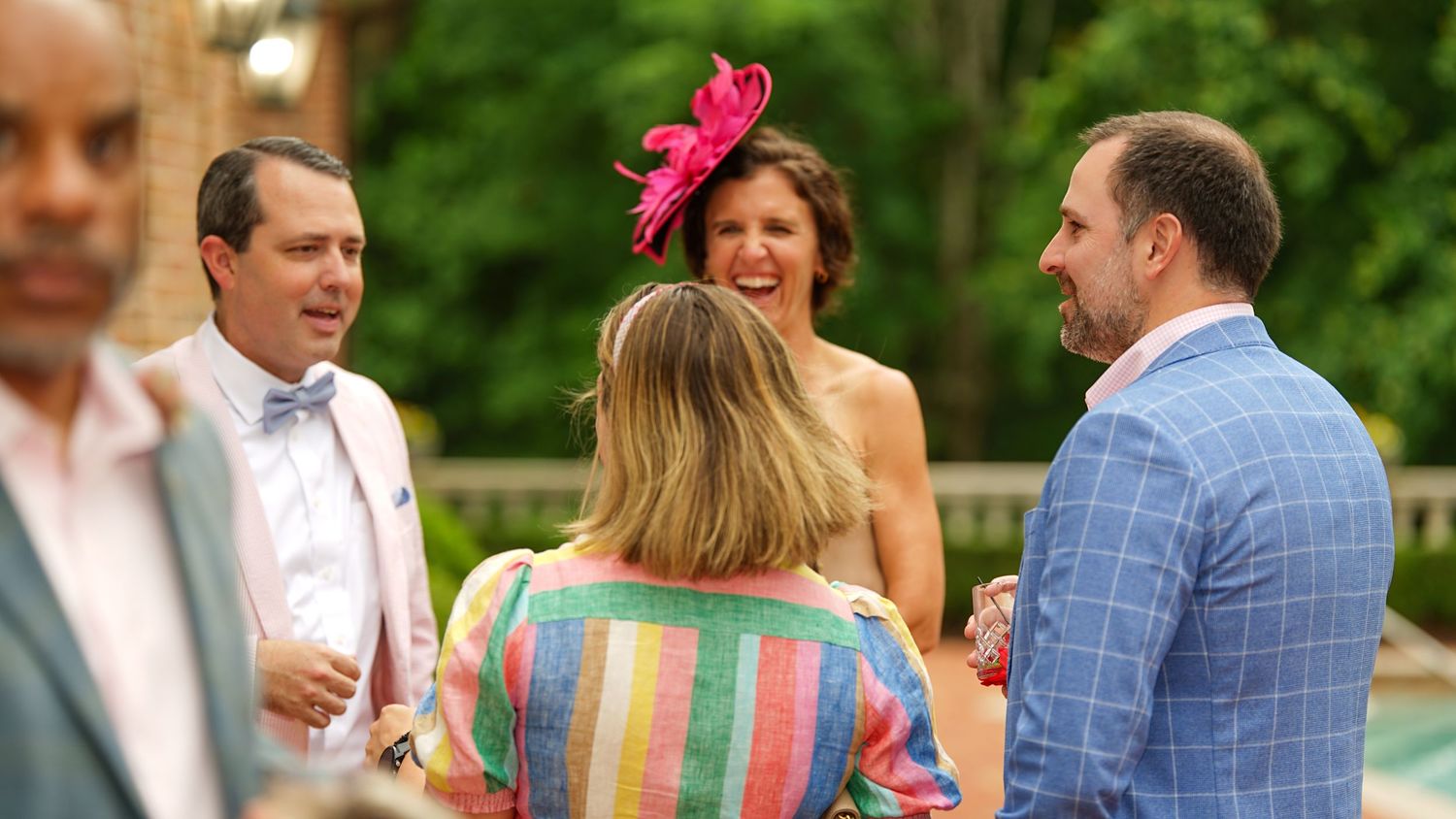 Guests enjoying a festive outdoor celebration with colorful attire and drinks.
