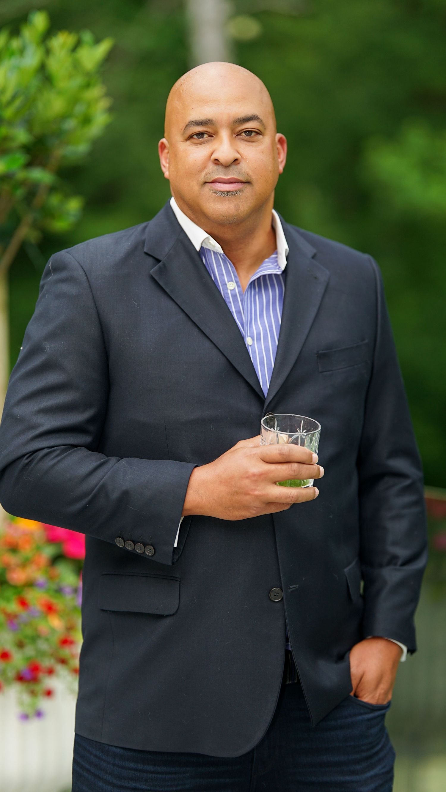 Series of shots showing person in dark suit holding a drink outdoors.
