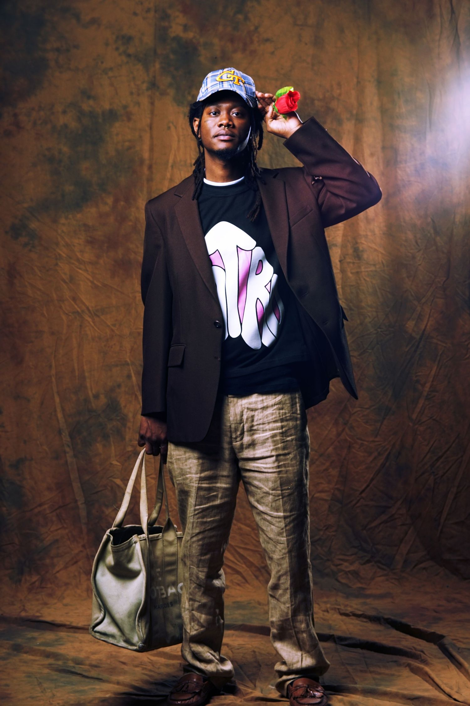 Fashion shoot against textured brown backdrop featuring casual urban streetwear and accessories.