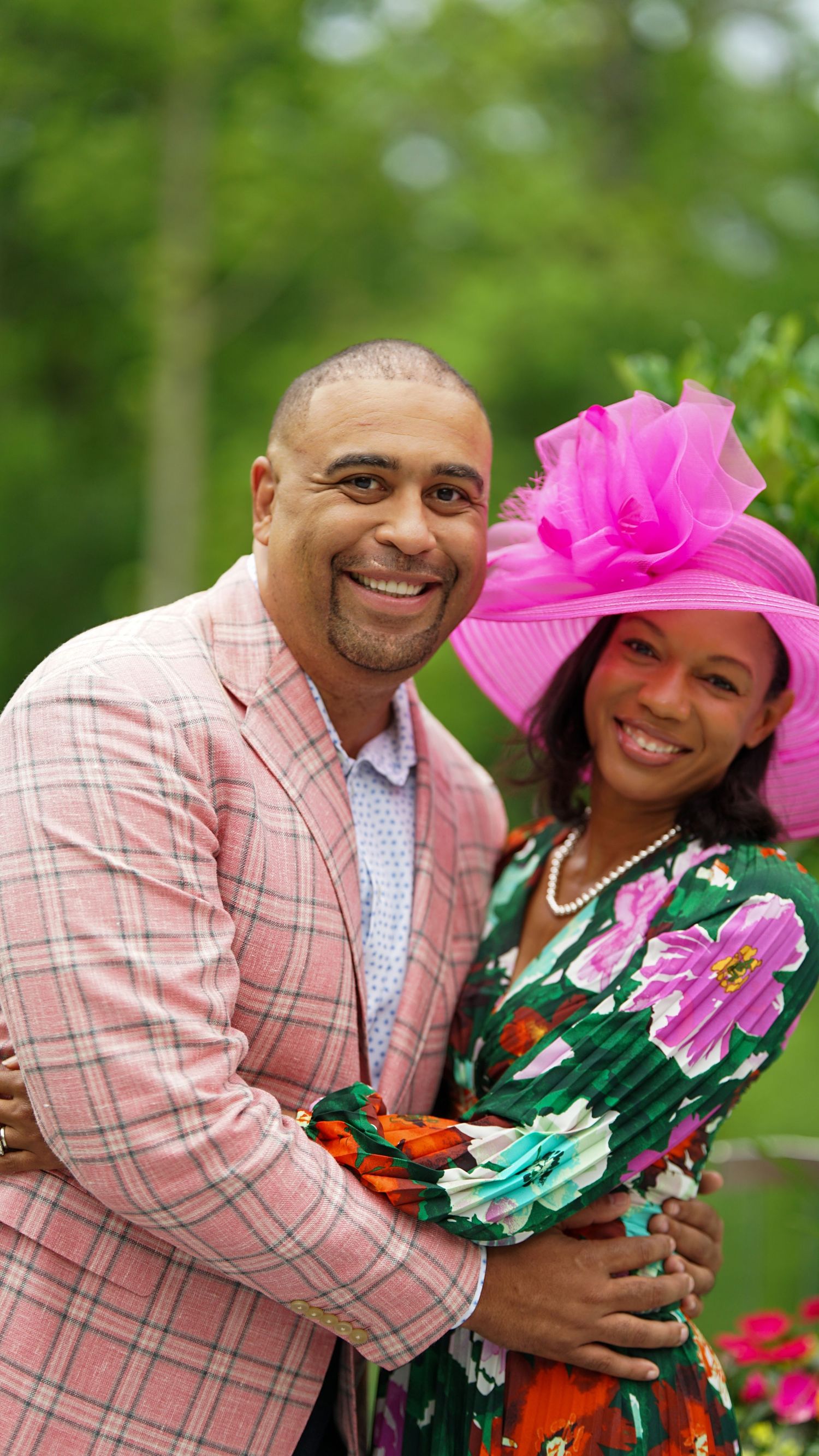 Couple in coordinated formal wear posing together at an outdoor garden event.