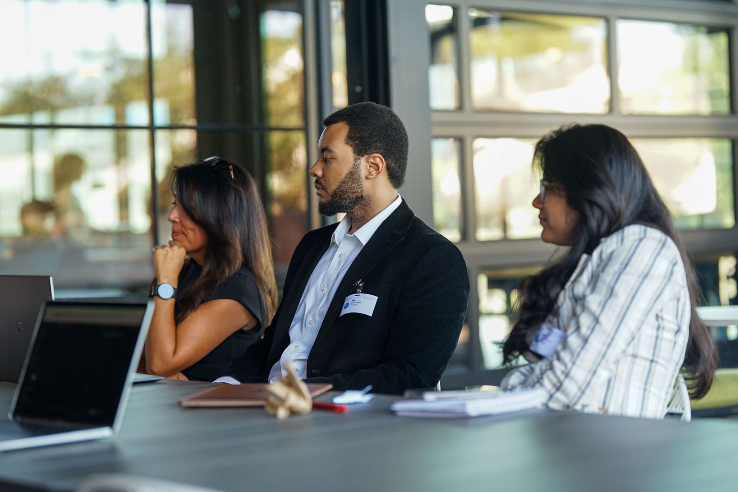 Three professionals sitting at a conference table during a business meeting in a modern office.
