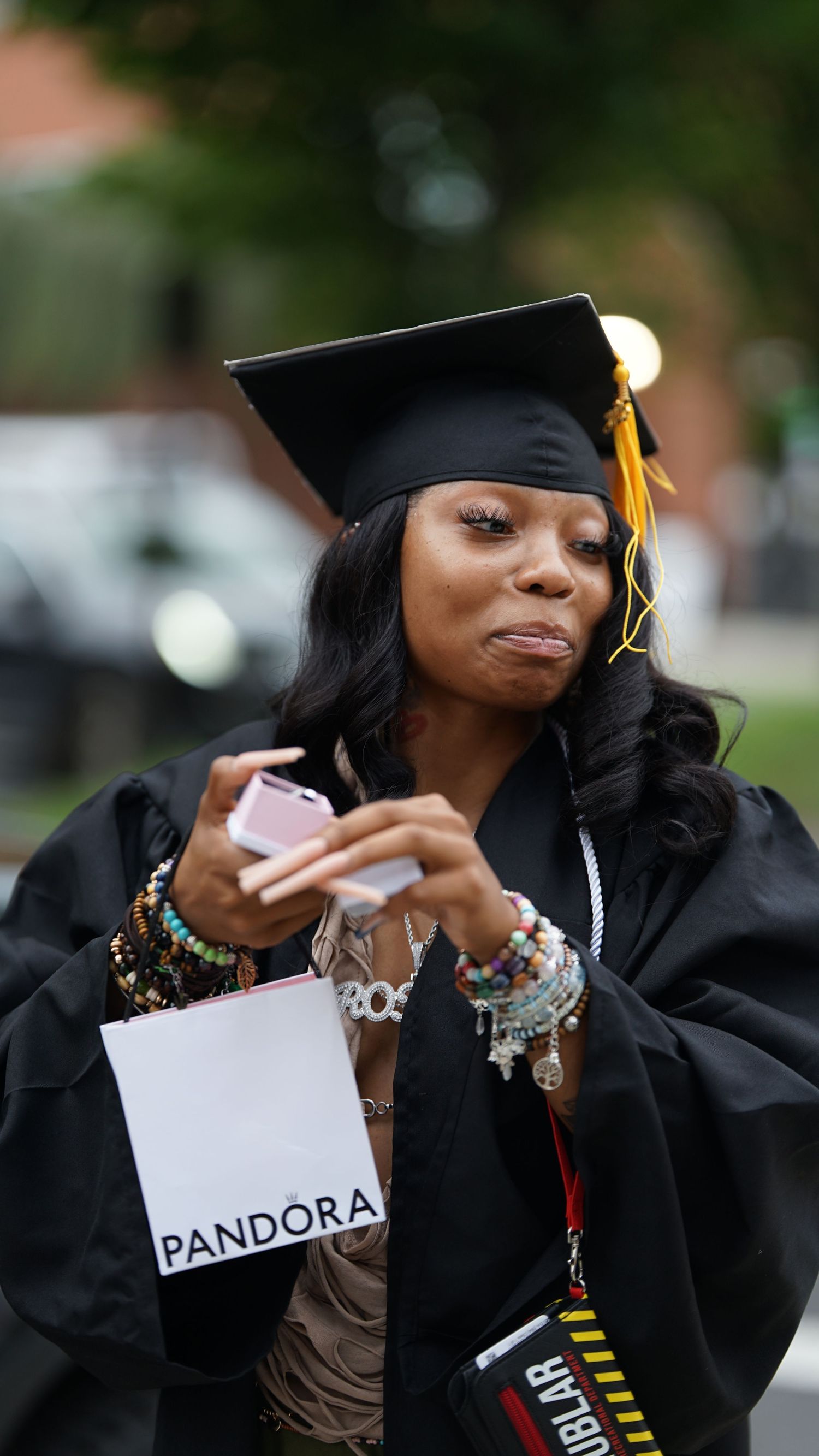 Graduate in black cap and gown reads Pandora letter with excitement.