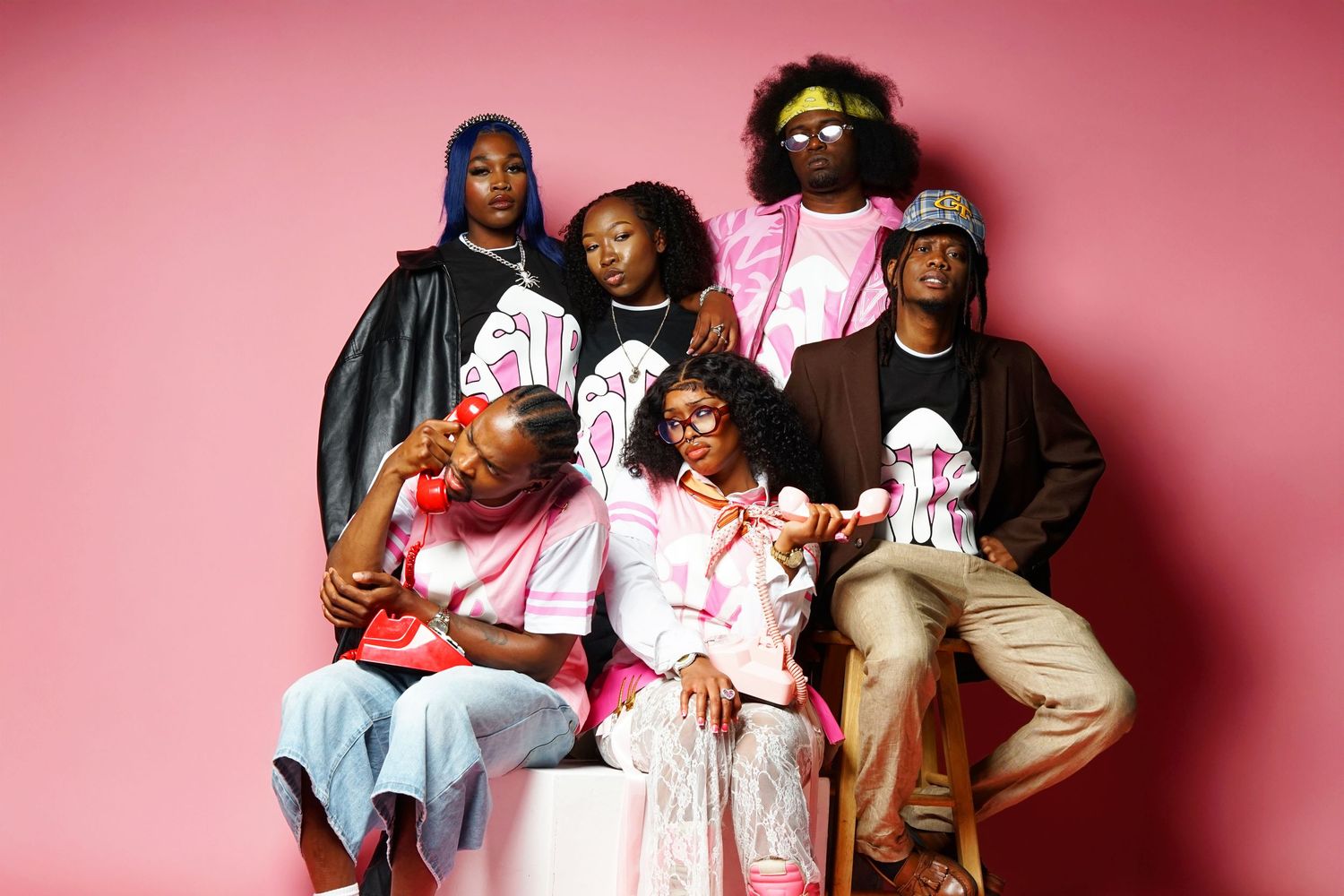 Group fashion photoshoot with models in coordinated pink and white outfits.