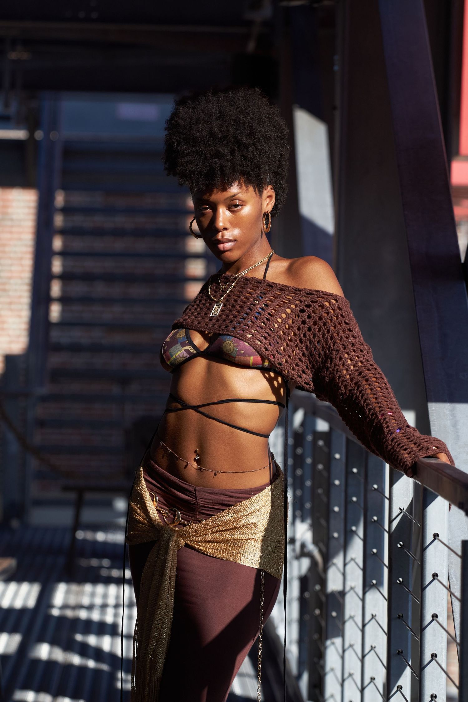 Fashion model in brown knit top strikes artistic poses in urban setting with dramatic shadows.