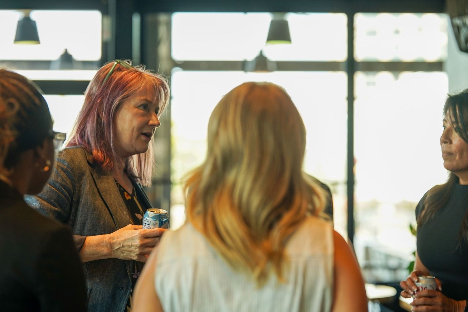 Women networking and conversing at a professional business event indoors.