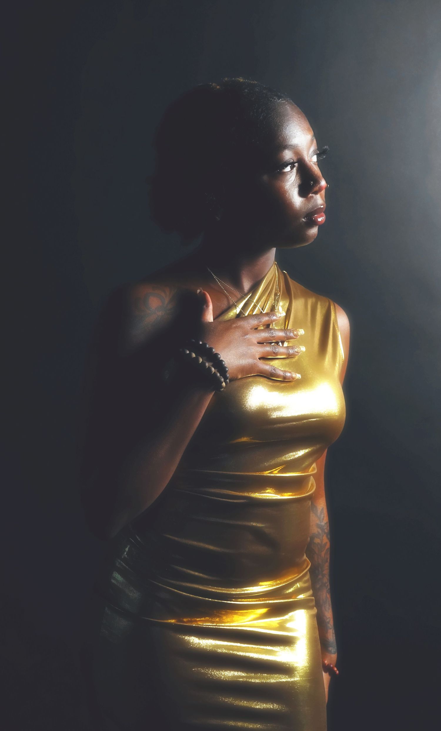 Dramatic photos in low light wearing a metallic gold top with artistic lighting effects.