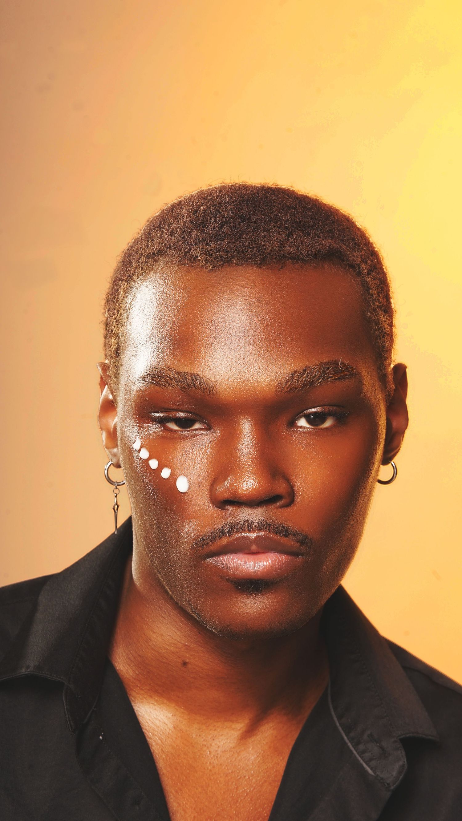Creative beauty portrait with decorative white dots against warm orange background.