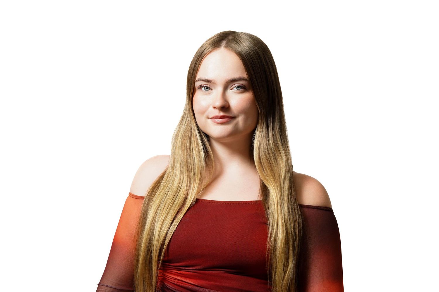 Young woman with long blonde hair wearing a red off-shoulder dress, posing against a white background.