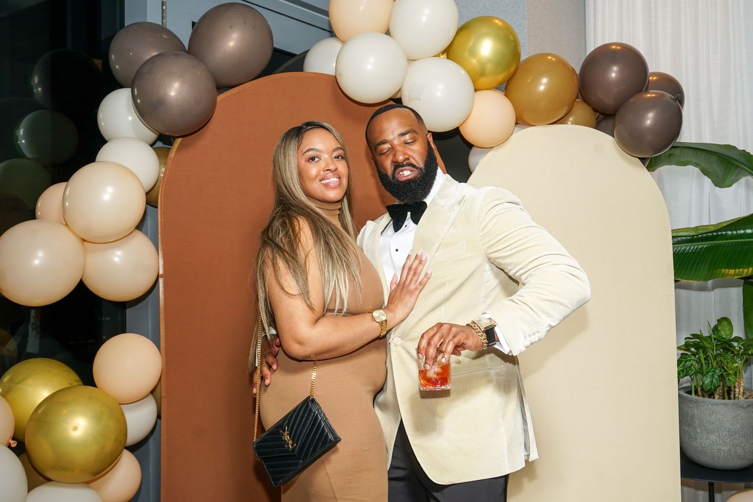 Couple posing together in front of colorful balloon arch backdrop at elegant event.