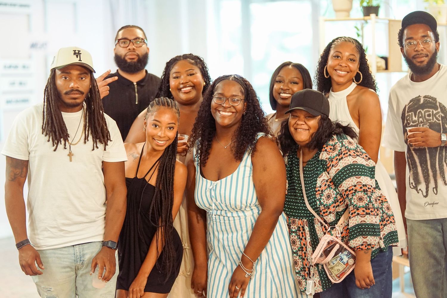 A joyful group of Black friends and family smiling together at a casual indoor gathering.