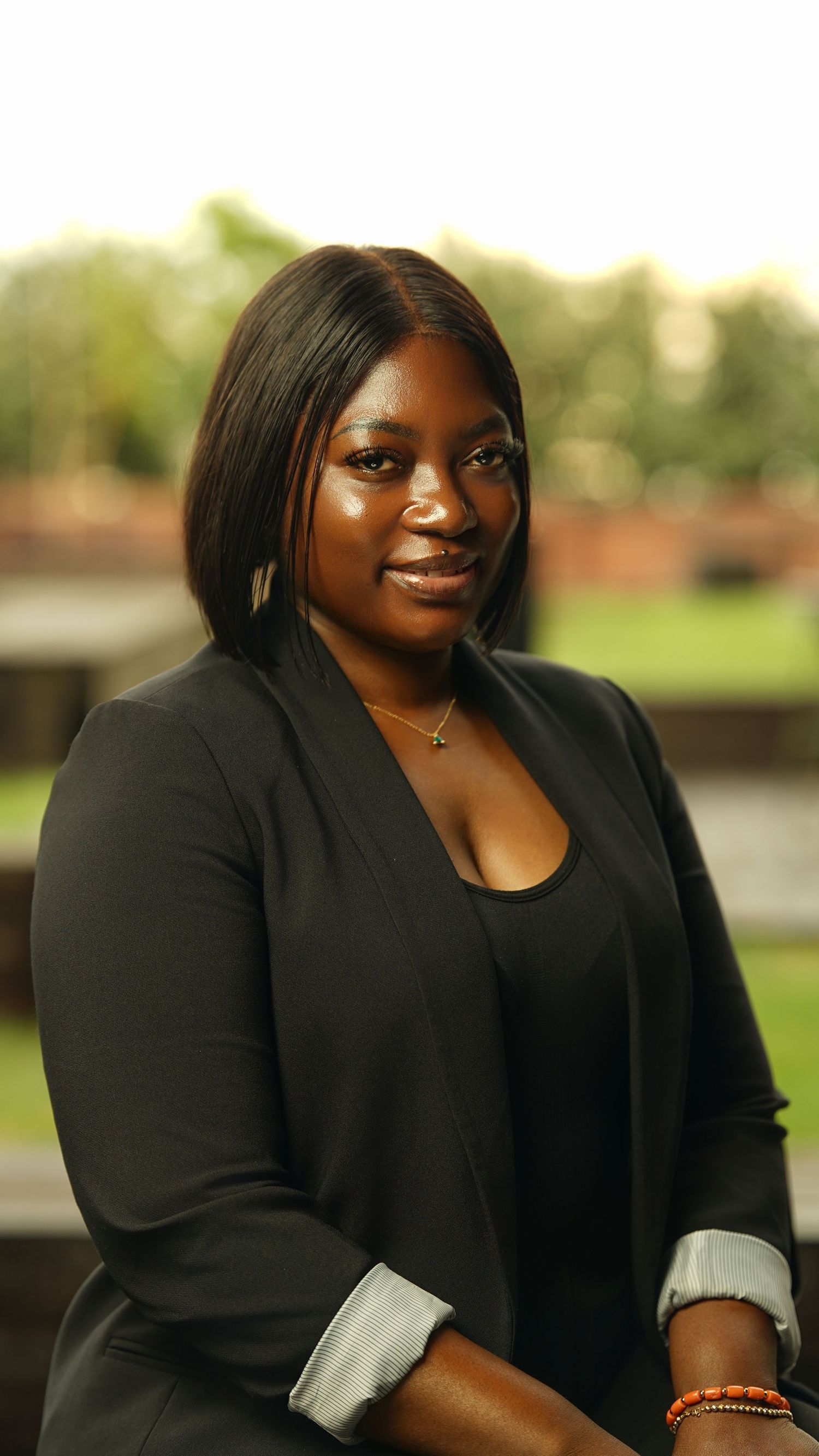 Portrait series showing someone in a black blazer with jewelry against an outdoor background.
