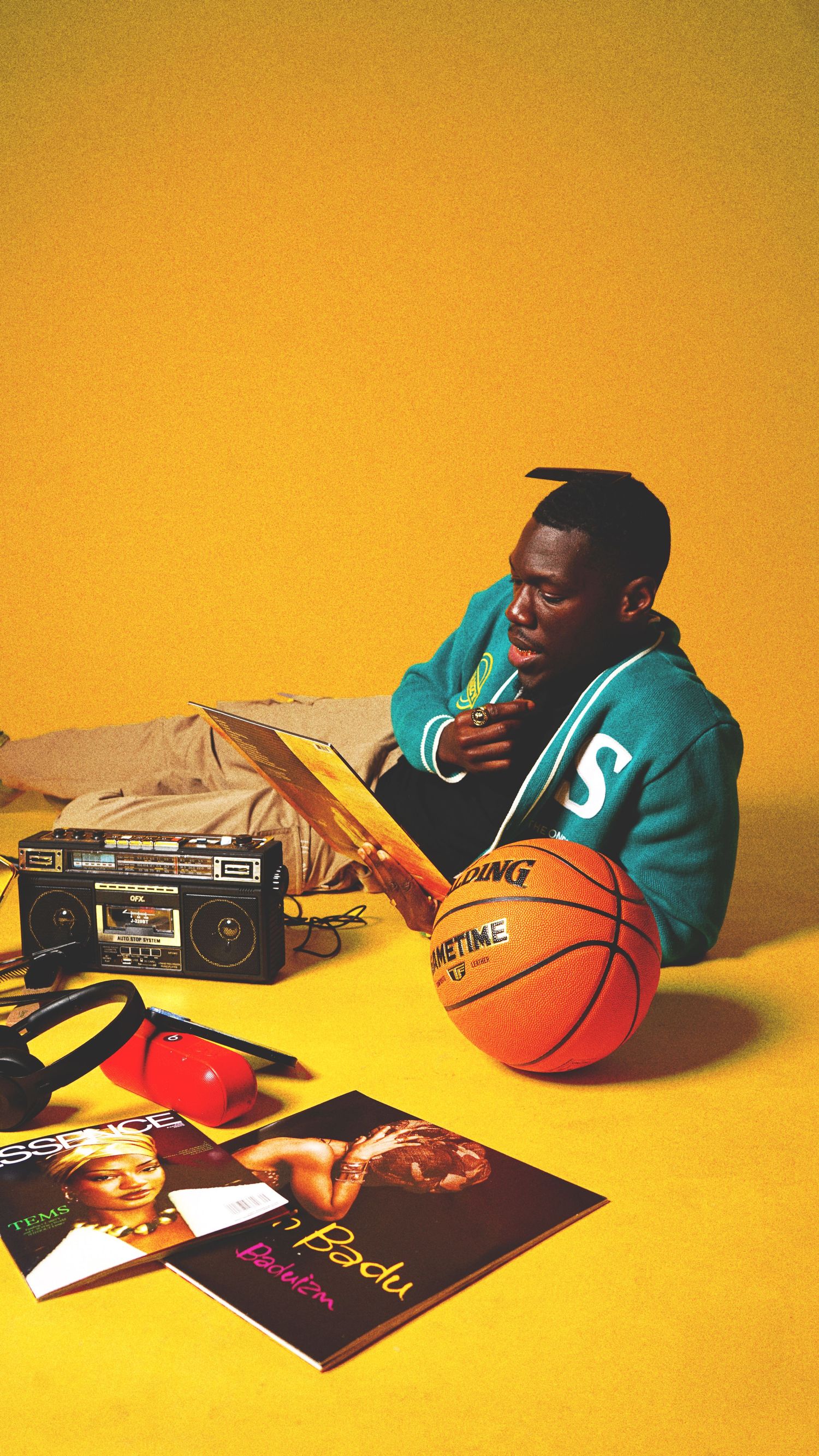 Basketball and books arranged on yellow background with person in teal sweater.