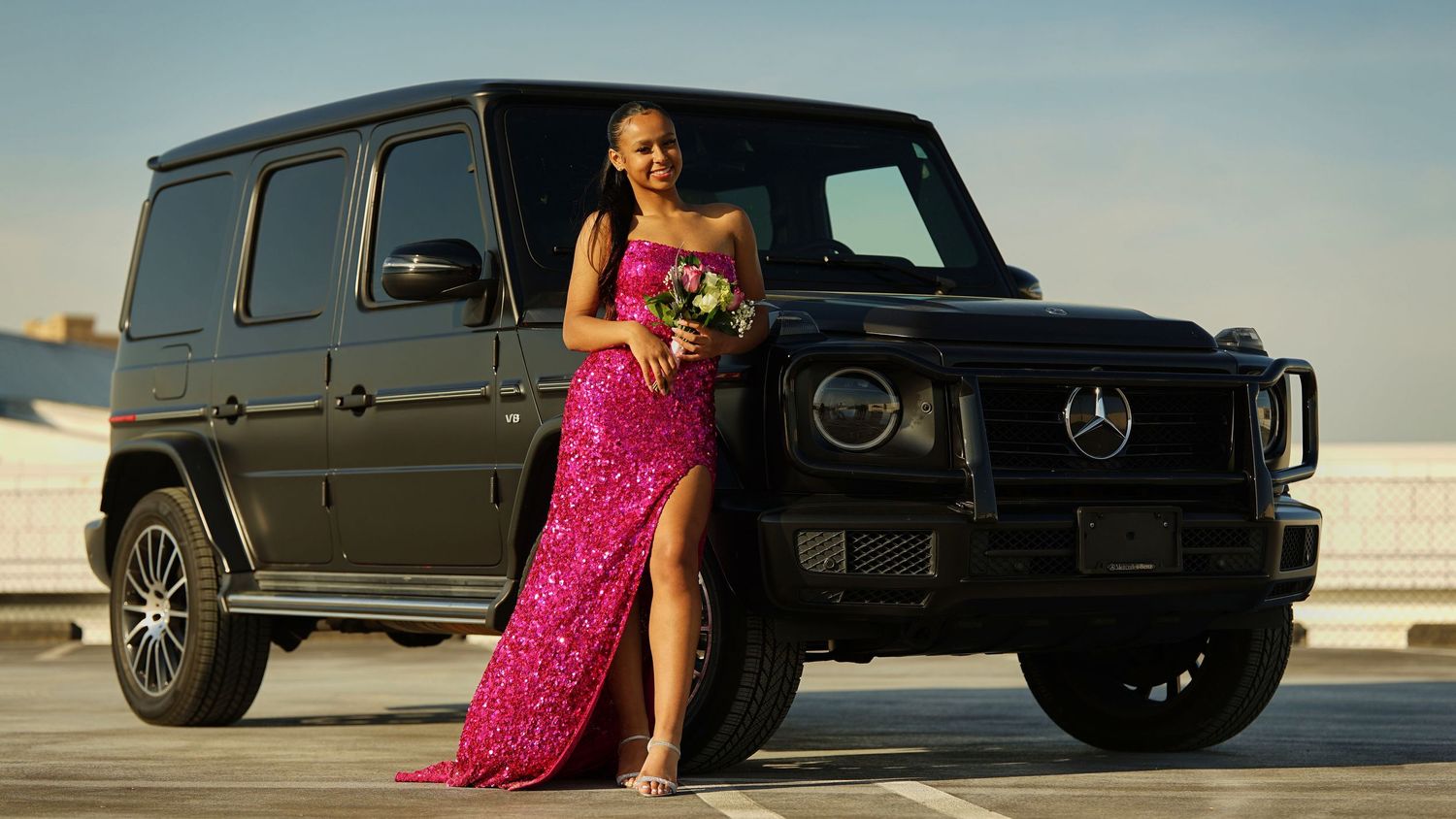 Pink sequin gown photographed next to luxury black SUV in outdoor setting.
