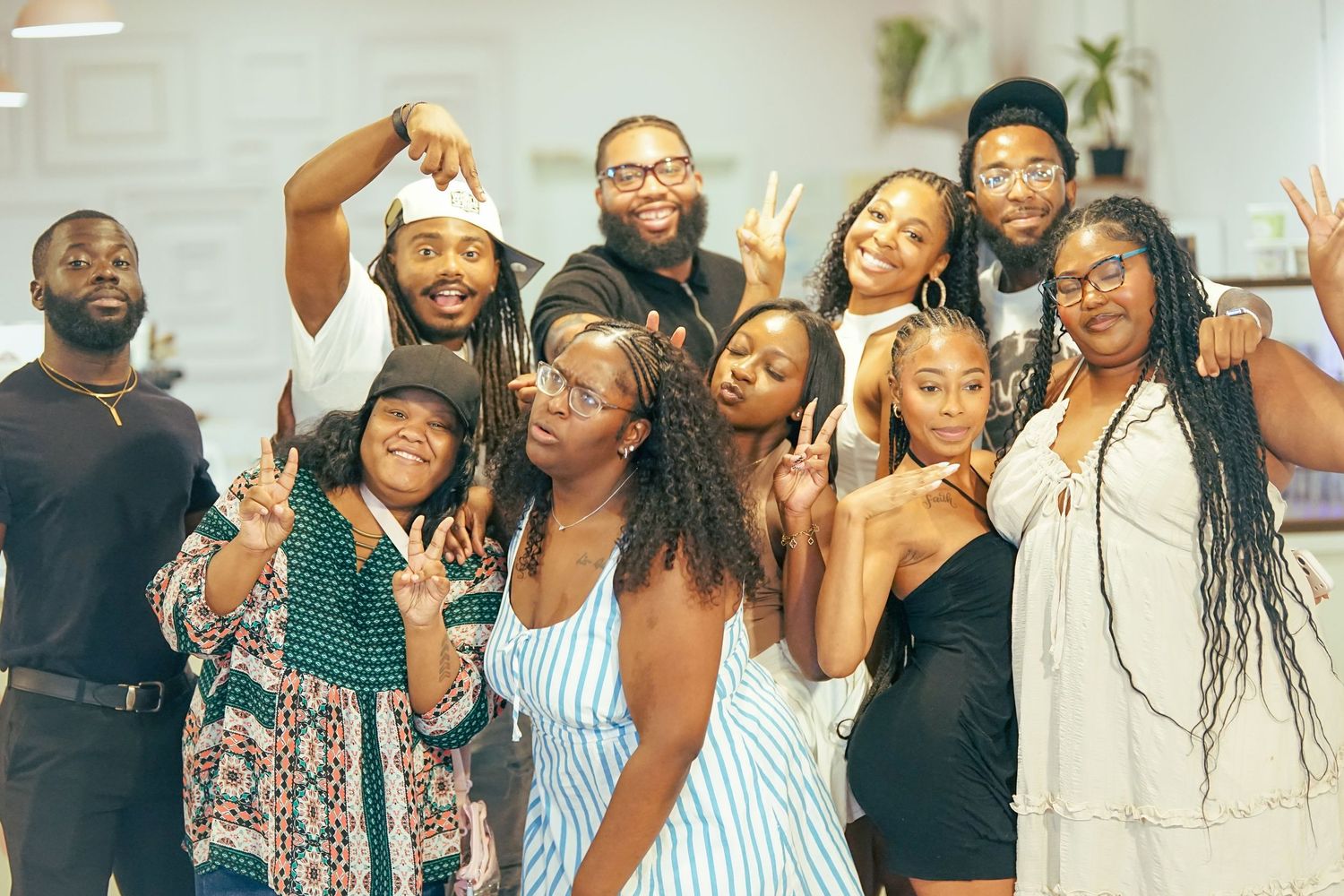 A diverse group of young Black adults pose together smiling and making peace signs.