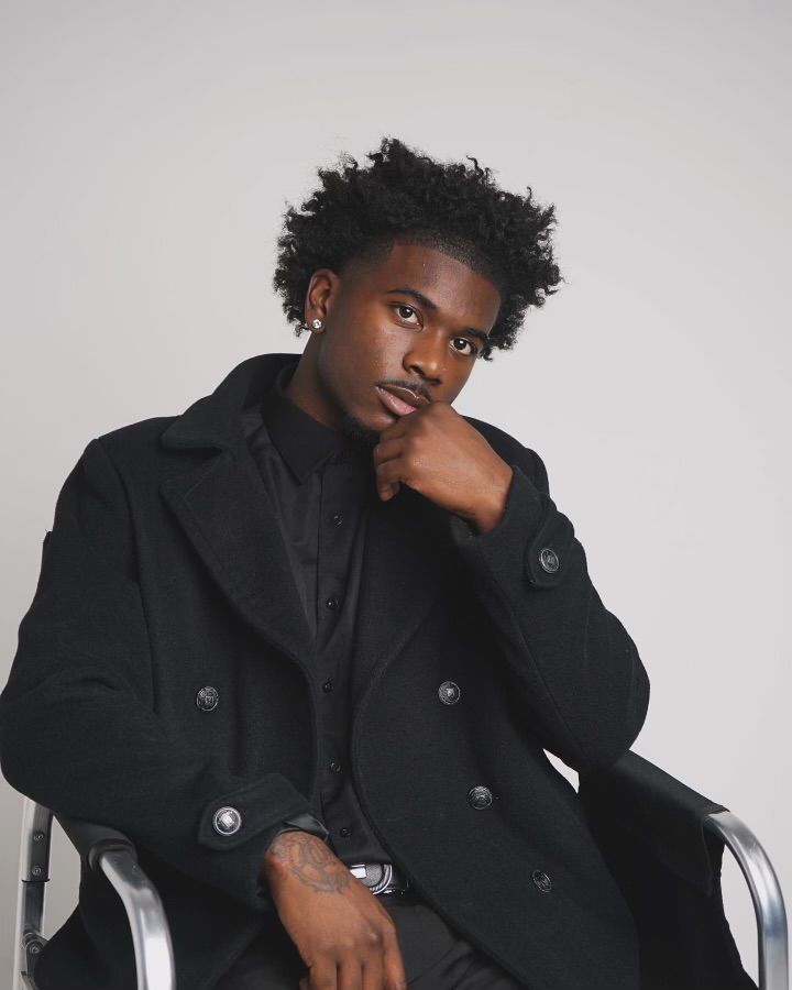 Fashion portrait featuring model in black peacoat against neutral background.