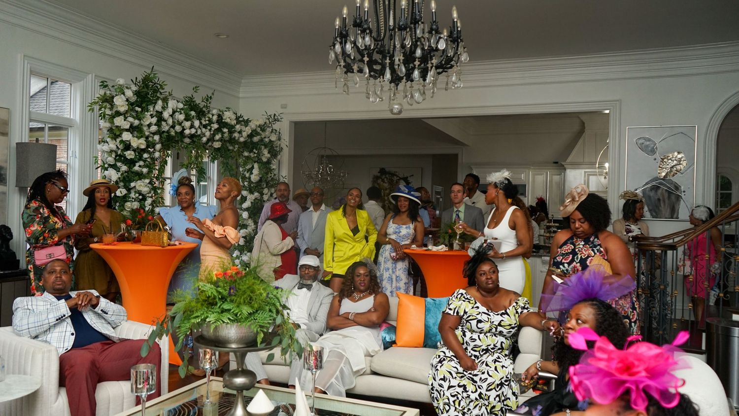 A panoramic view of an elegant indoor party venue with chandeliers and orange decor accents.