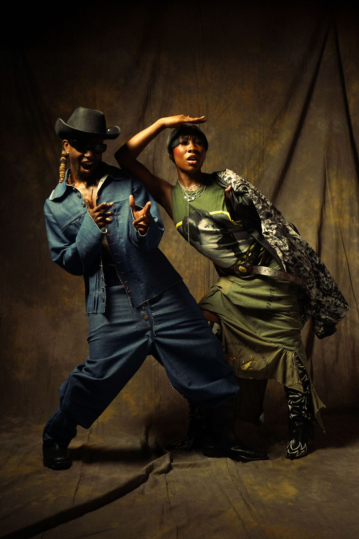 Two dancers perform dynamic dance moves against a dark wooden floor in a dramatic sequence of motion.