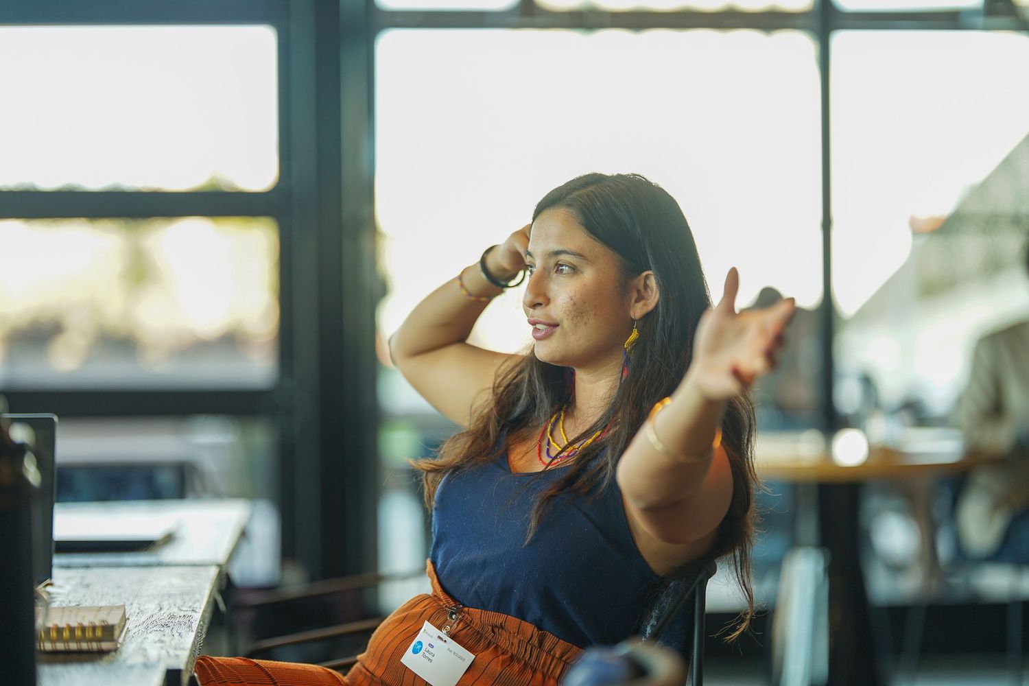 Young woman gesturing expressively during a business meeting in a modern office space.