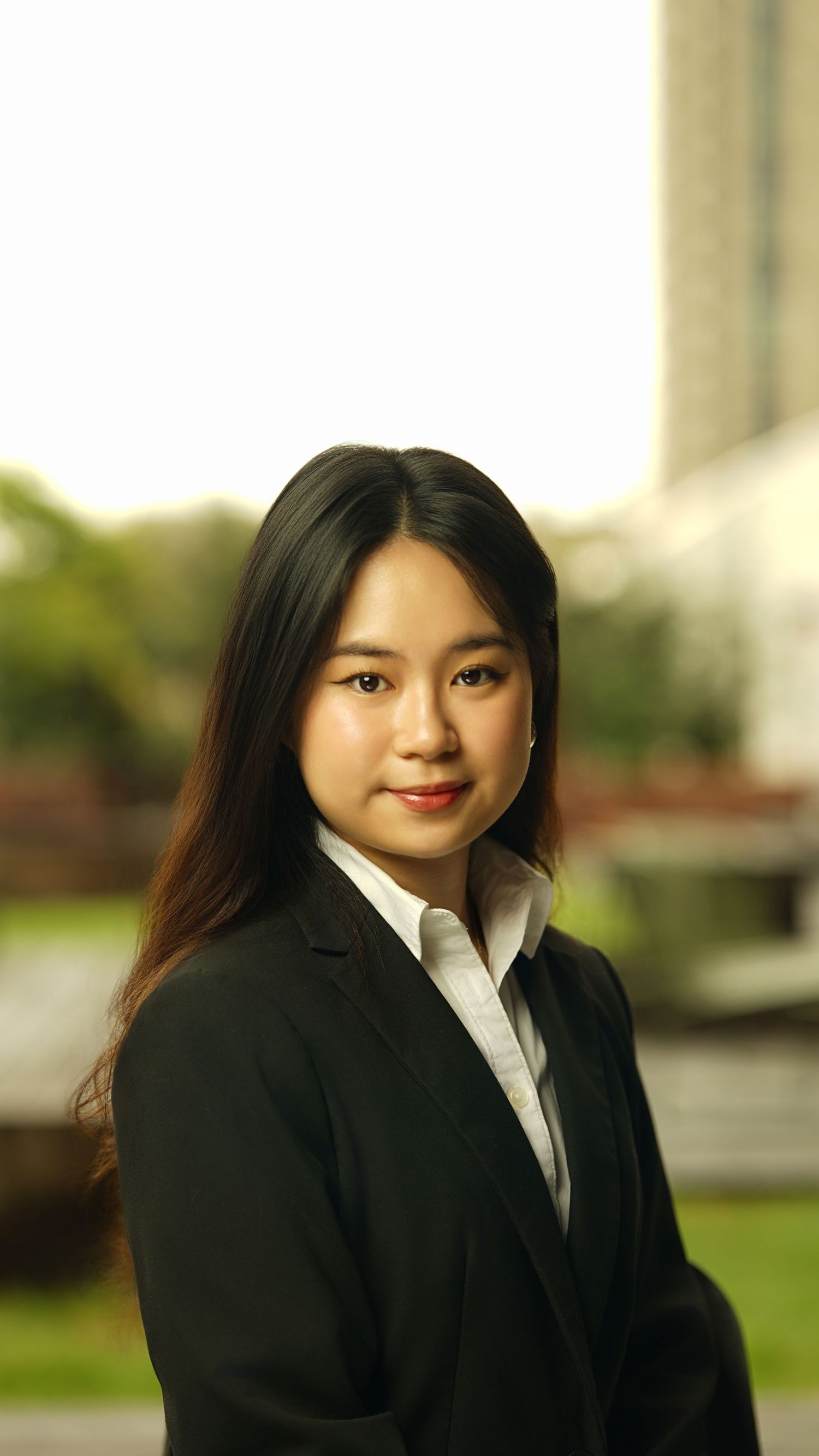 Professional headshot of a person in black suit and white collar against a light background.