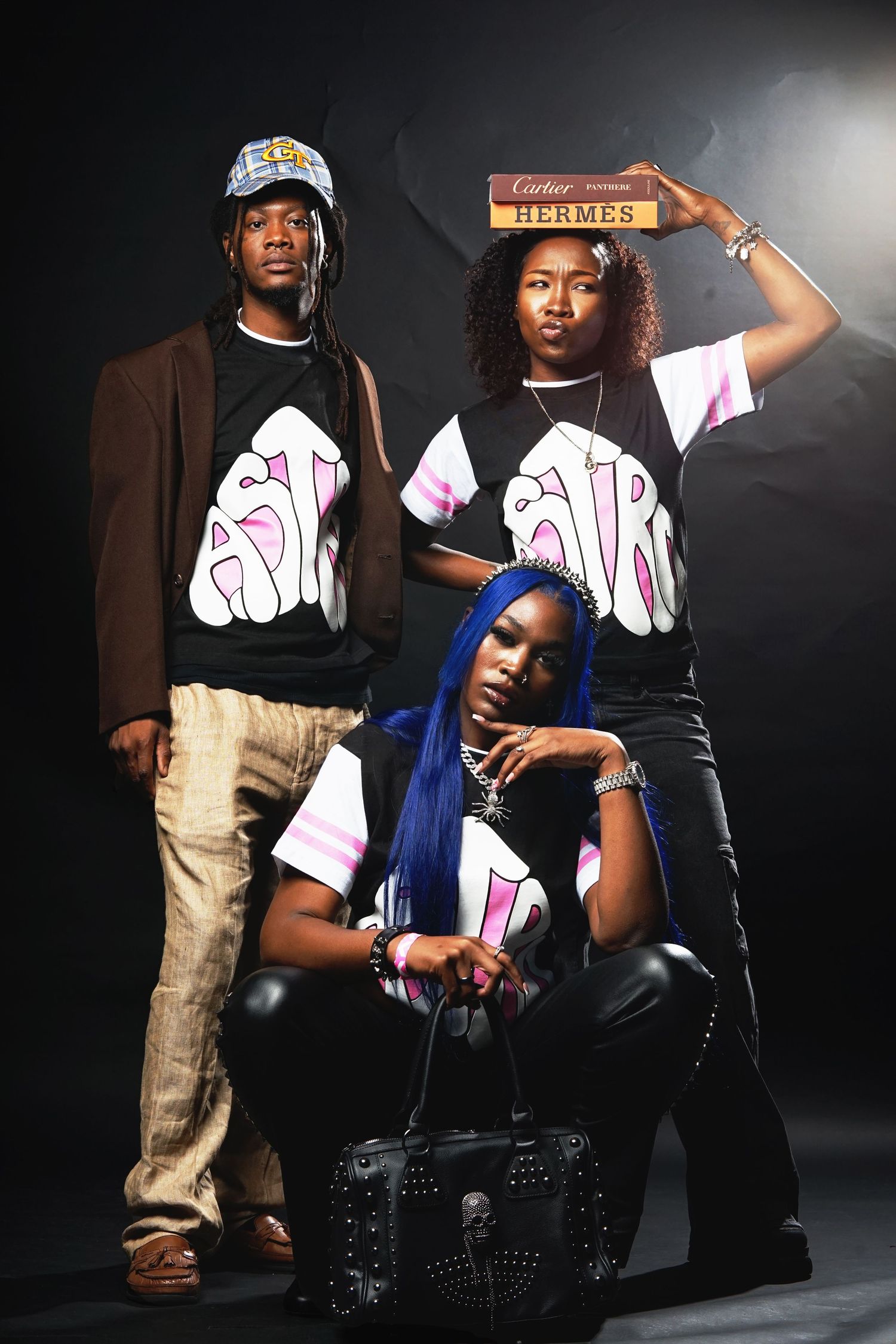 Creative fashion portrait of three models in matching graphic tees and varied poses.