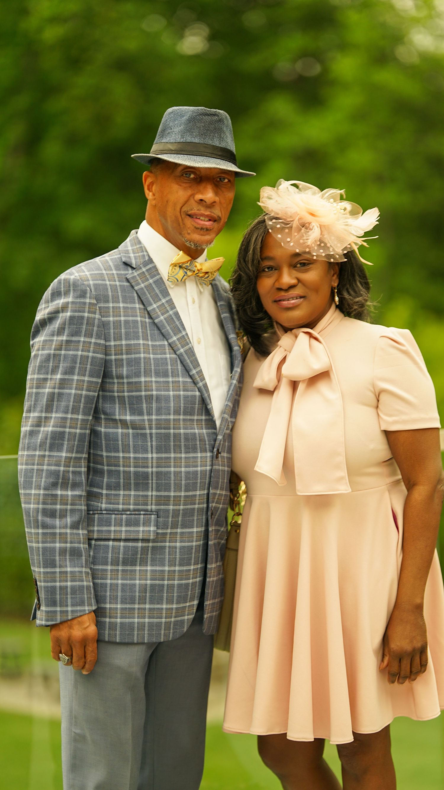 Couple in vintage-inspired derby attire with plaid blazer and peach dress with fascinator.