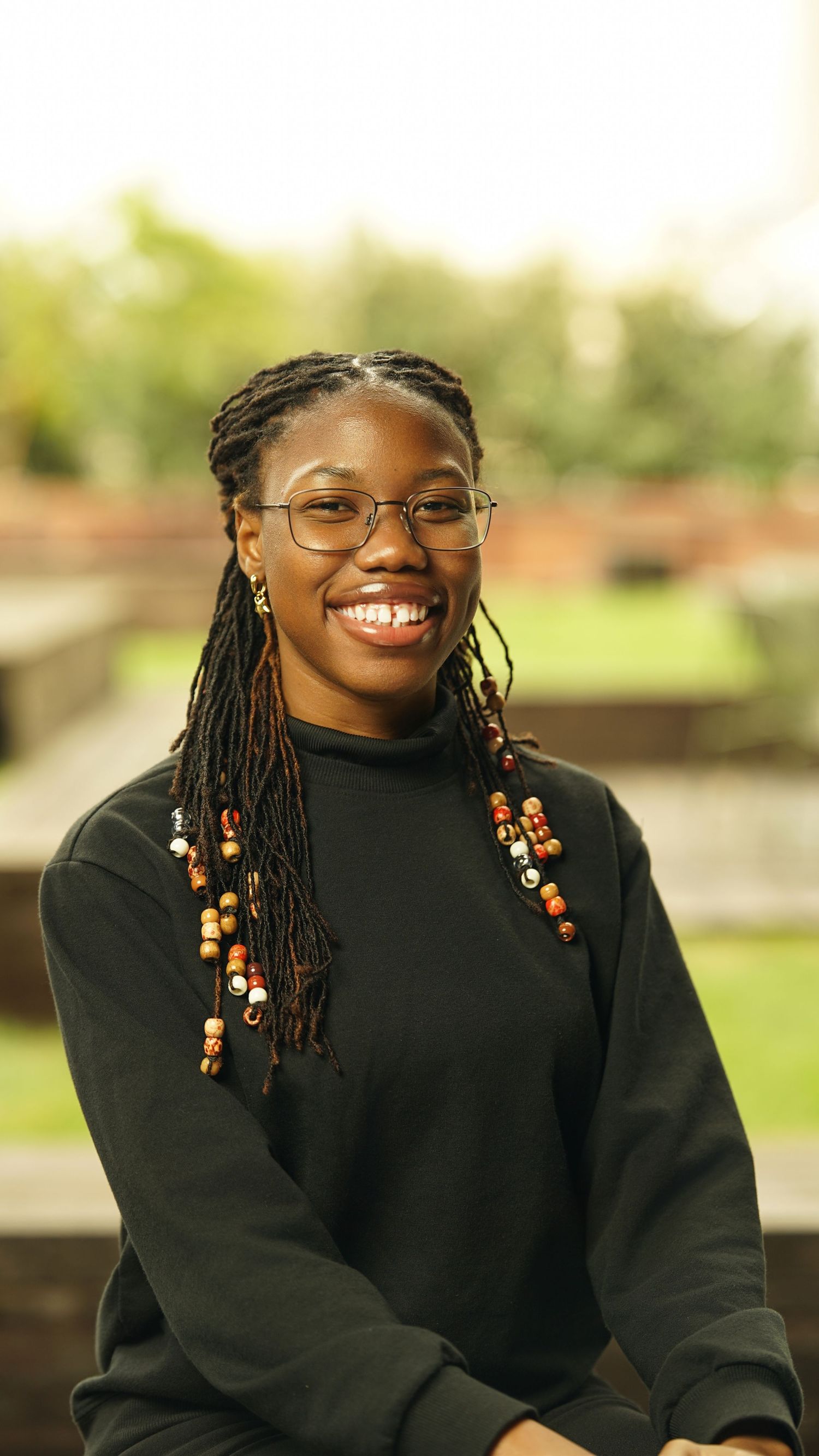 Portrait series showing someone in a black sweater with braided hair and beaded accessories.